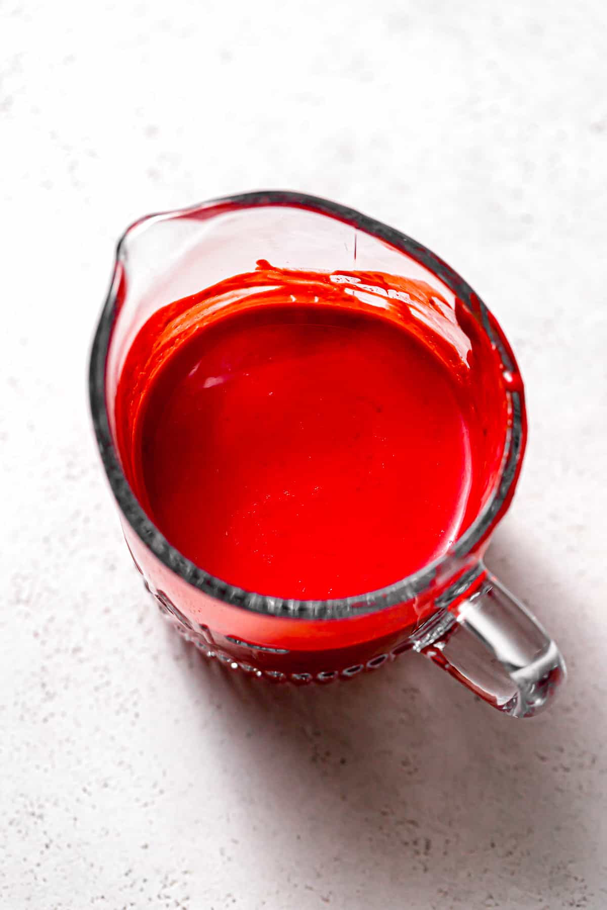 buttermilk colored red in glass measuring cup.