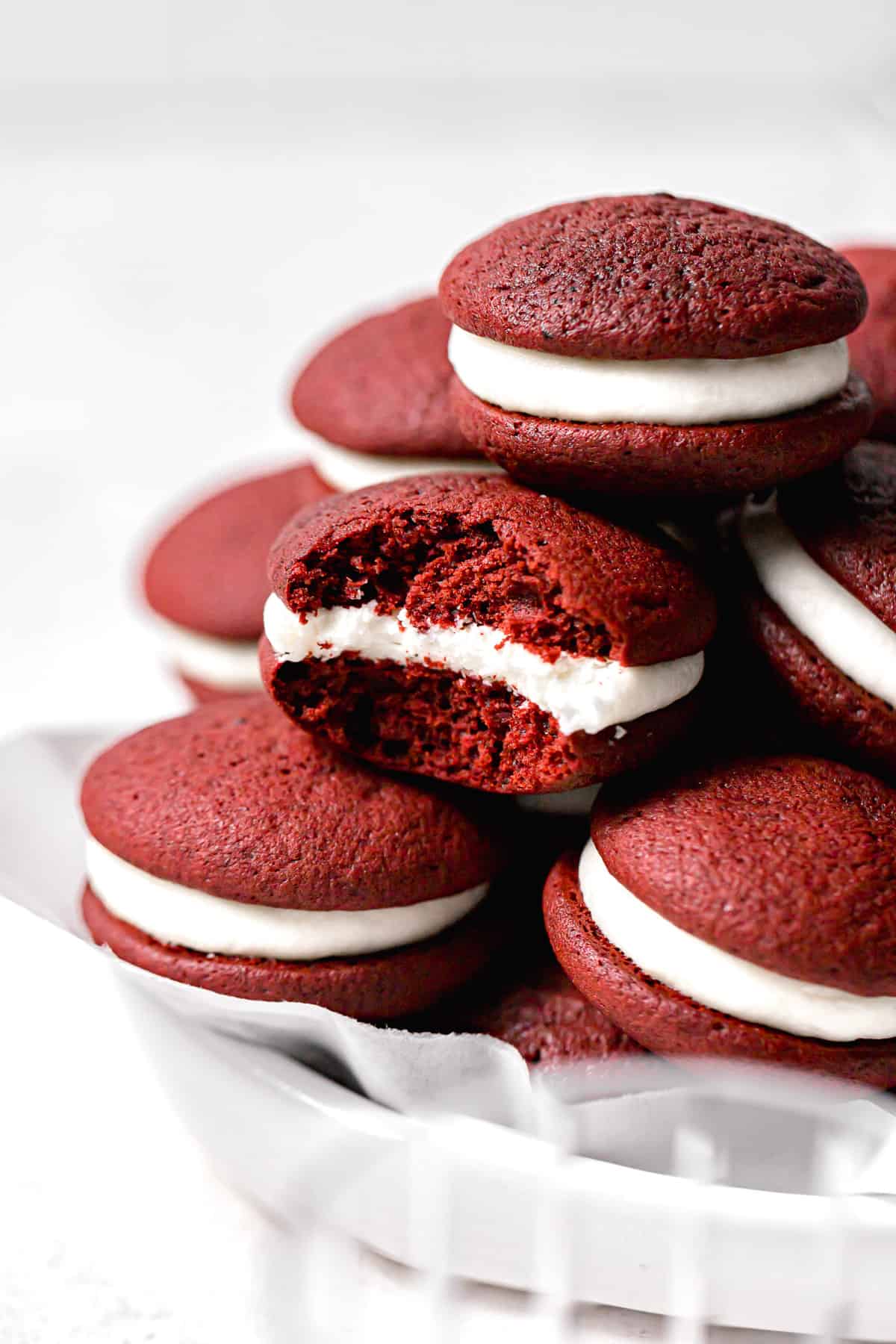 bite taken out of red velvet whoopie pie in the middle of a stack.