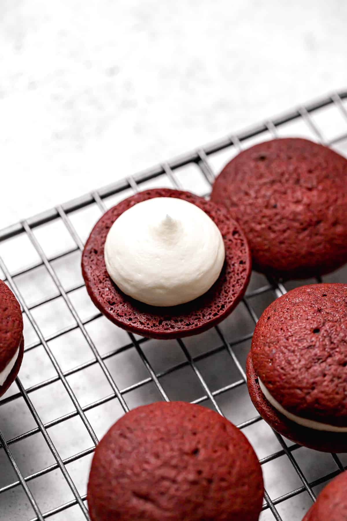 cream cheese frosting piped onto bottom whoopie pie on wire rack