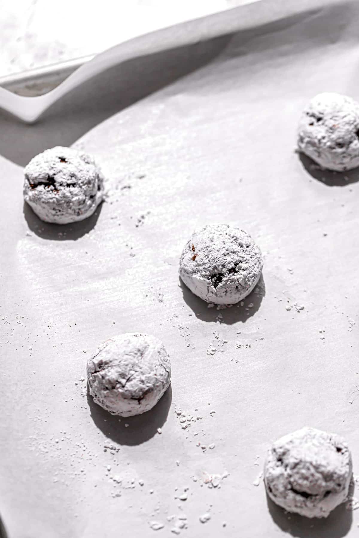 cookie dough coated in powder sugar on baking sheet.
