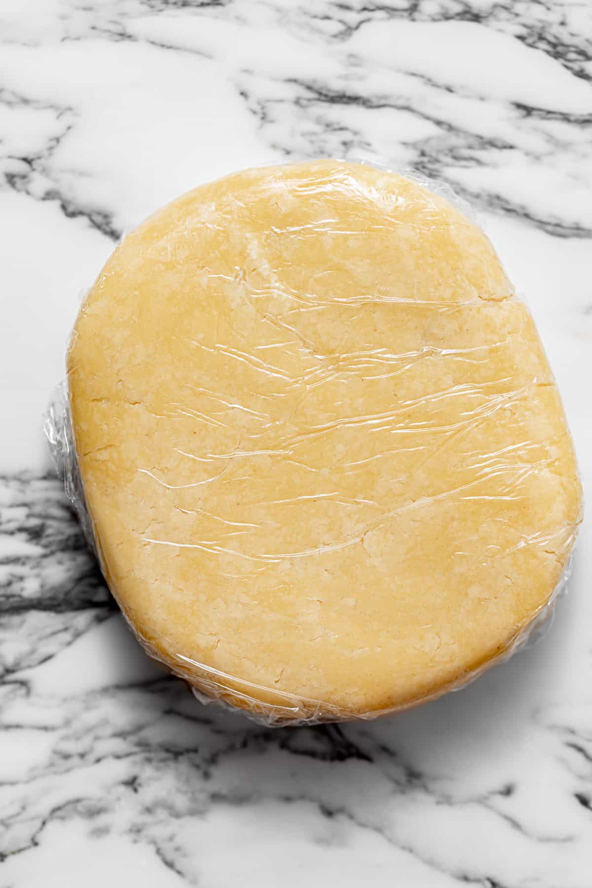 shortcrust pastry dough shaped into a disk and wrapped in plastic wrap.