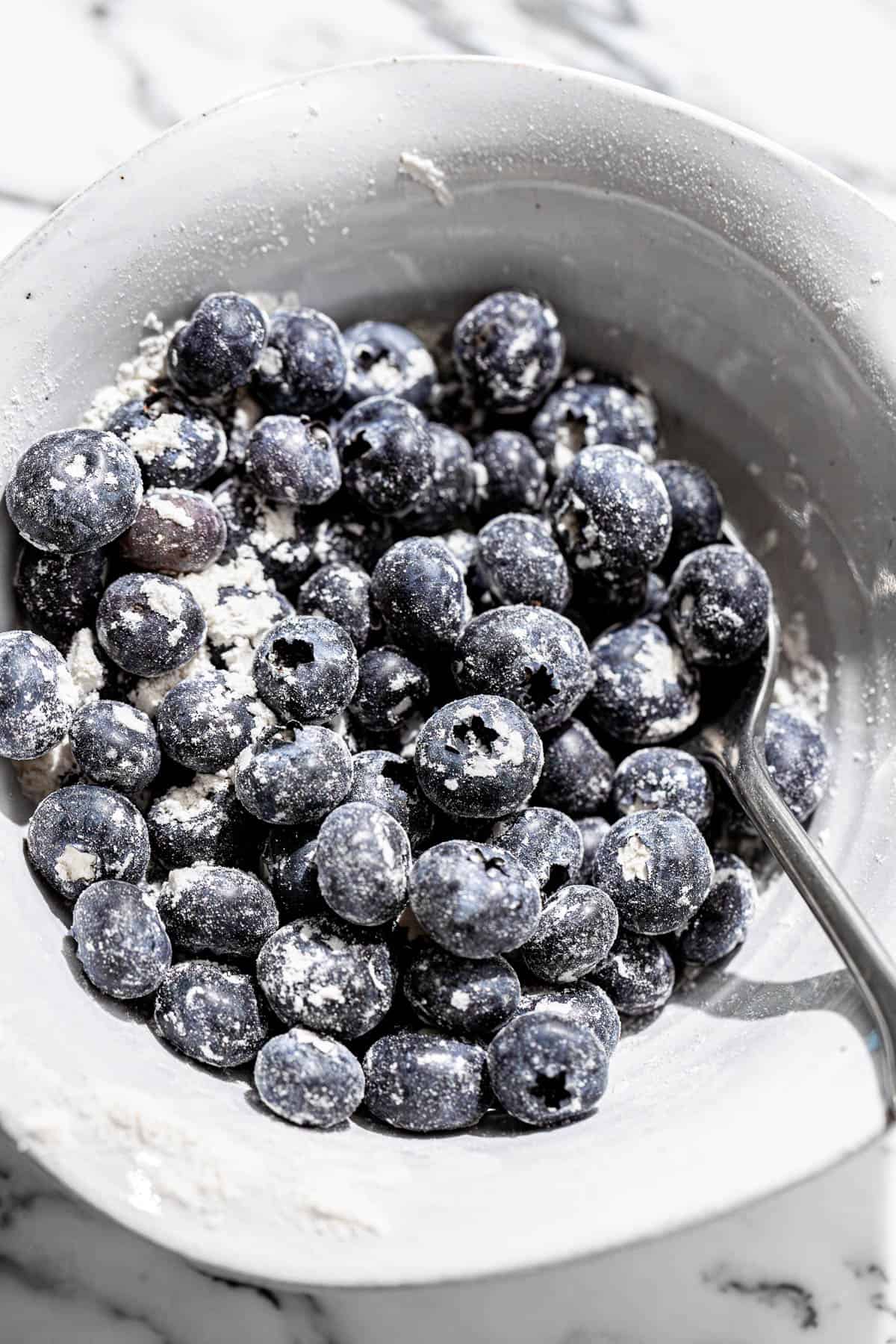 blueberries coated in flour in bowl.