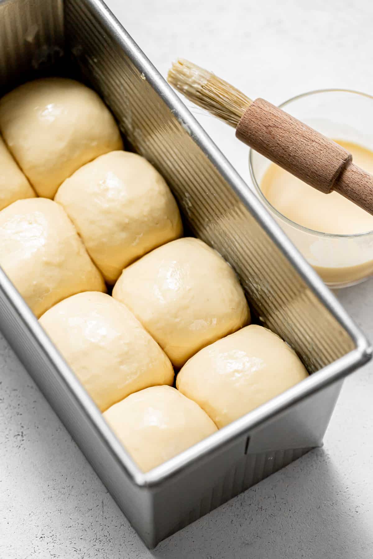 brioche bread dough balls arranged in pullman pan.