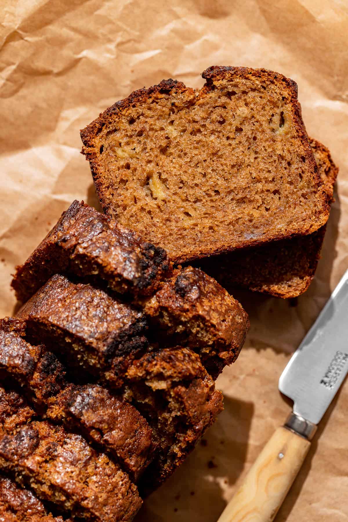 brown butter banana bread sliced on parchment paper. 