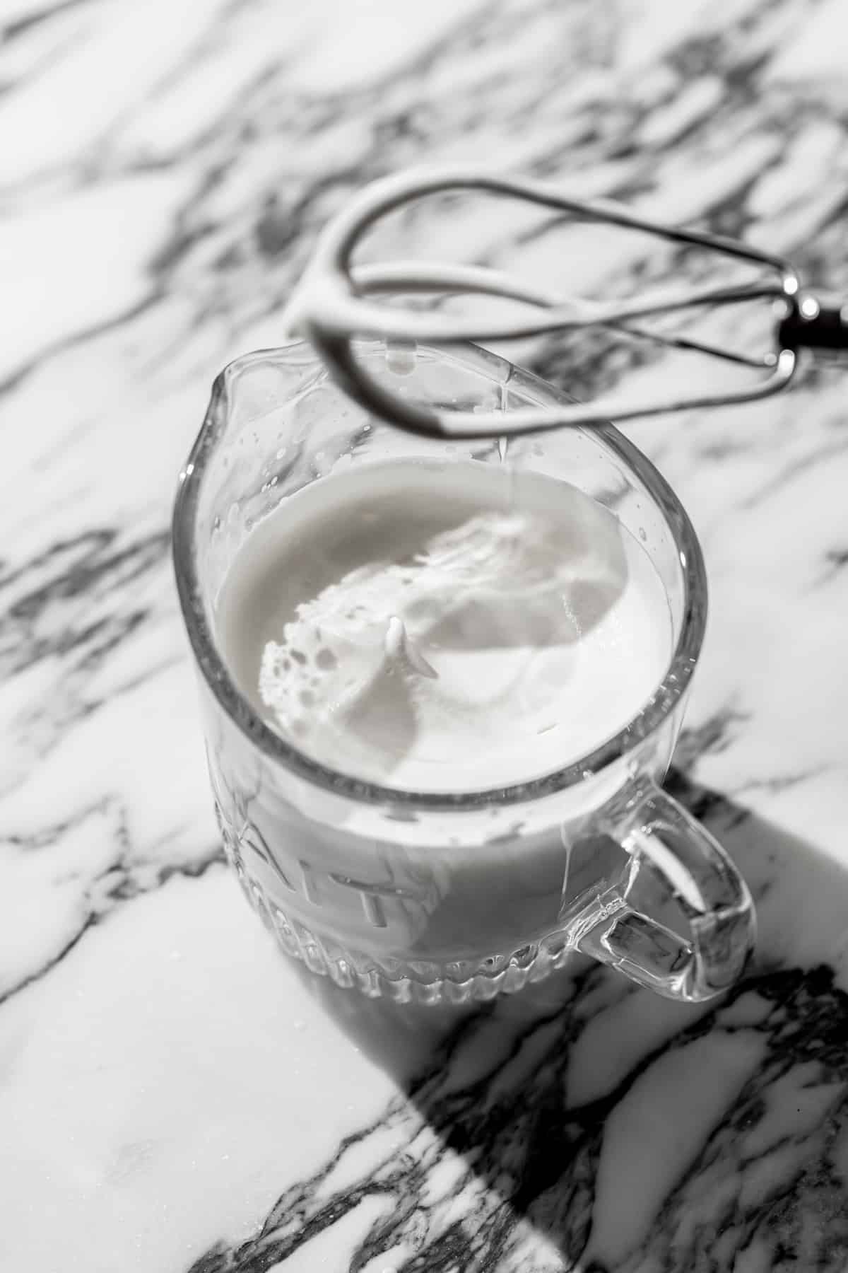whipped cream in glass measuring cup.