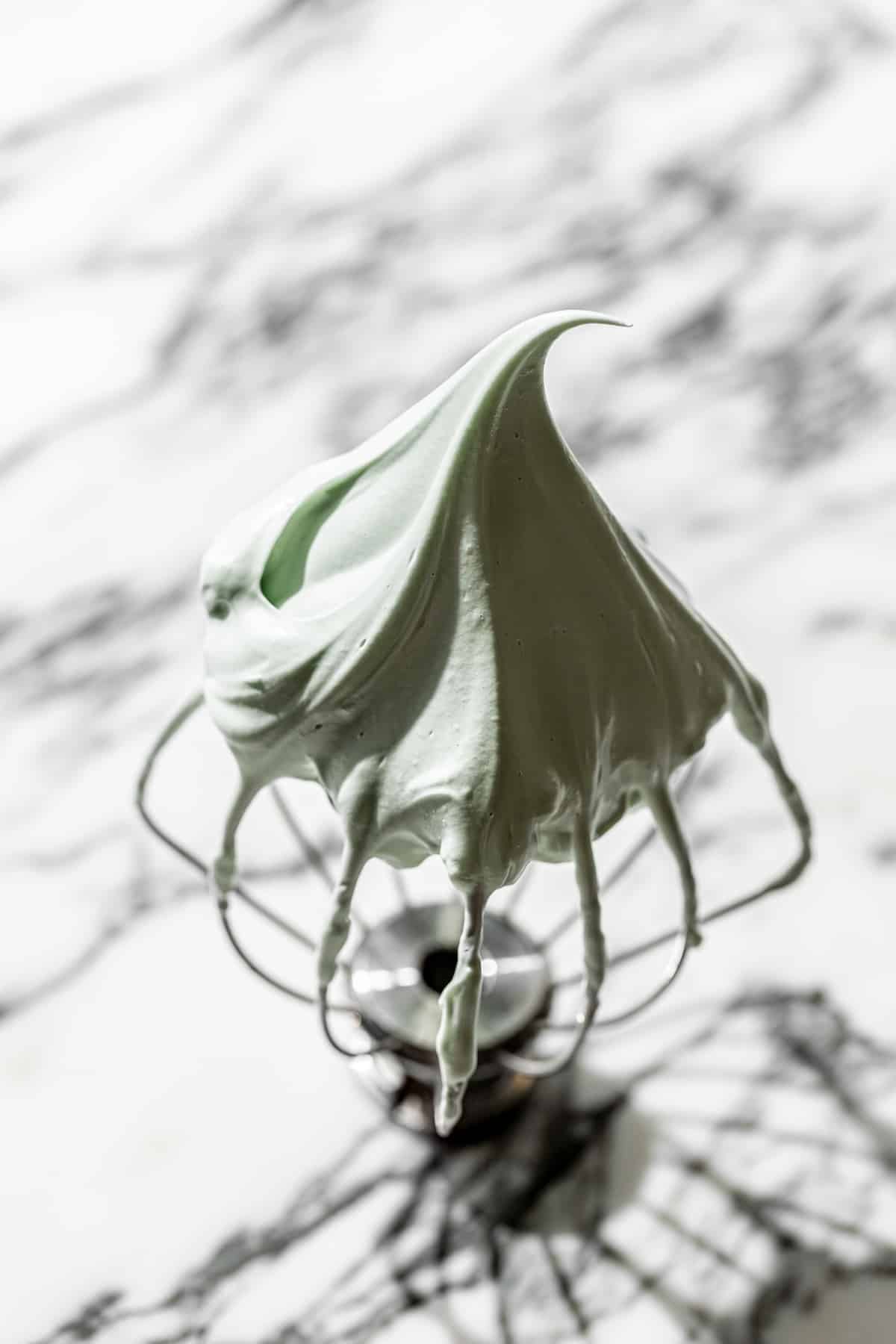 green colored meringue on whisk attachment. 