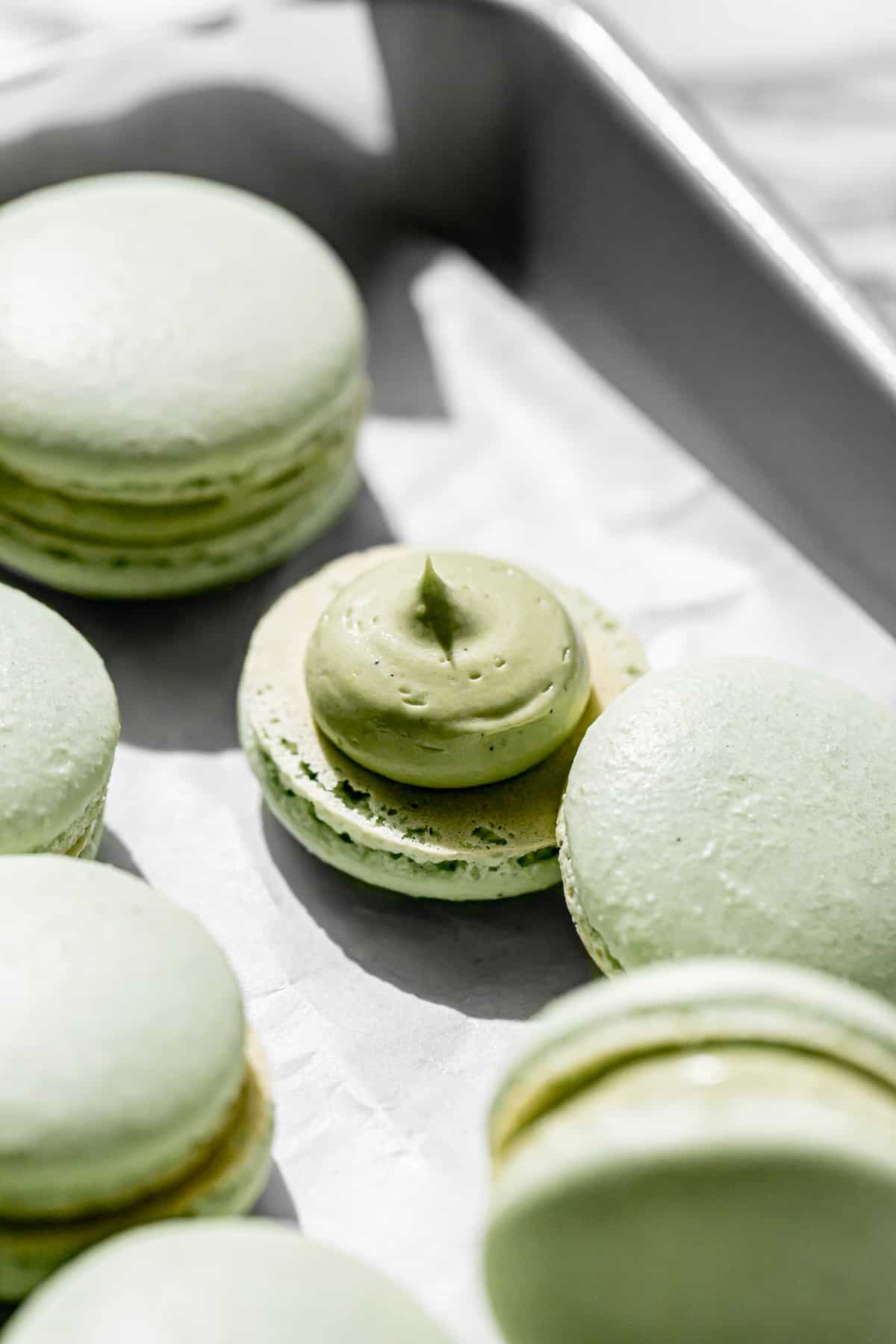 pistachio French buttercream piped onto one macaron shell. 