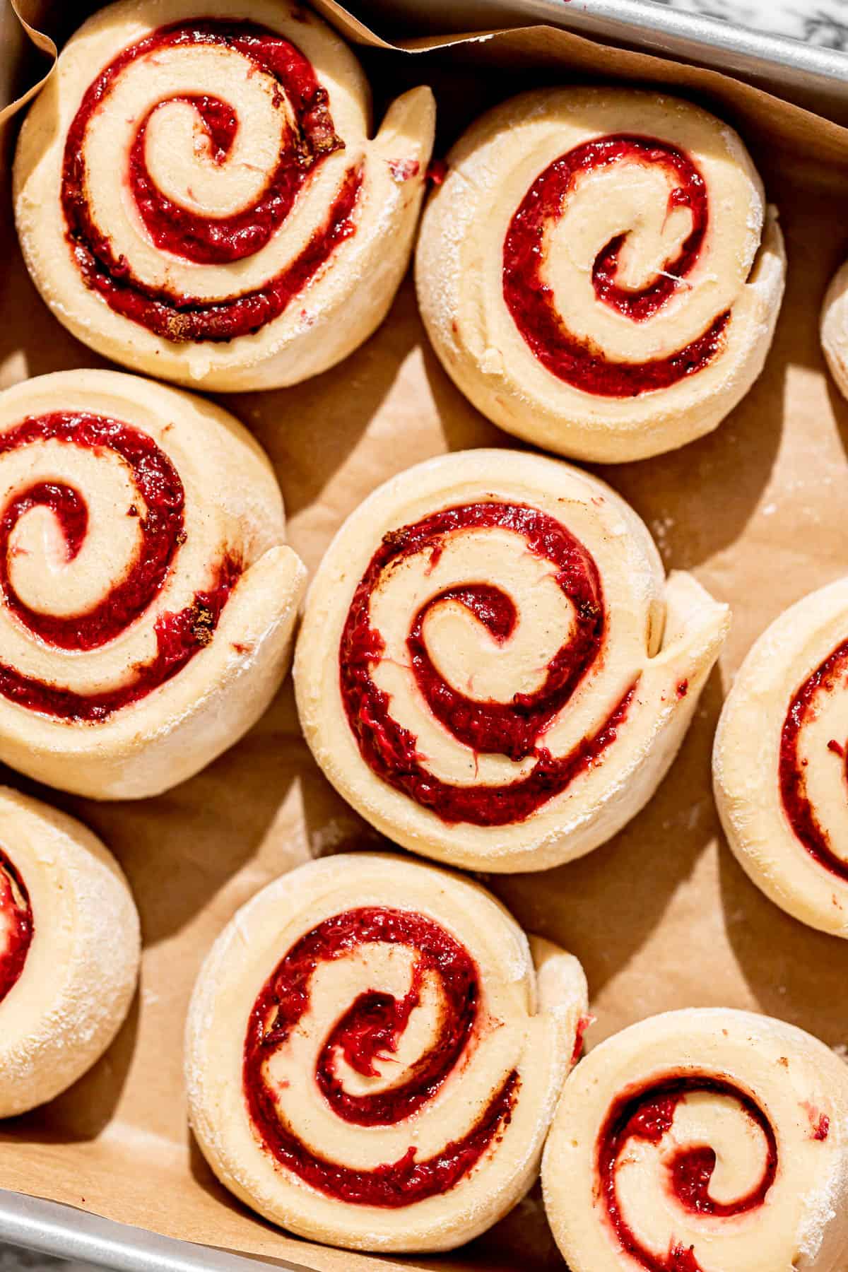 proofed strawberry cinnamon rolls in square pan. 