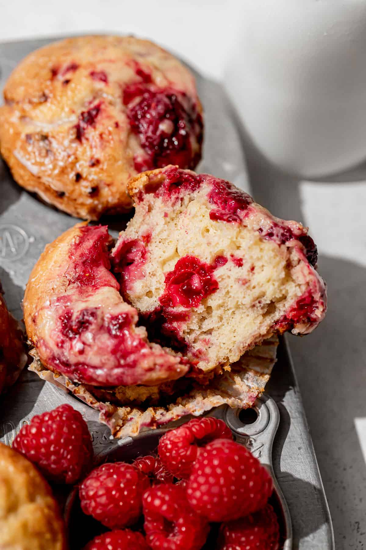 raspberry muffin cut in half in muffin pan.