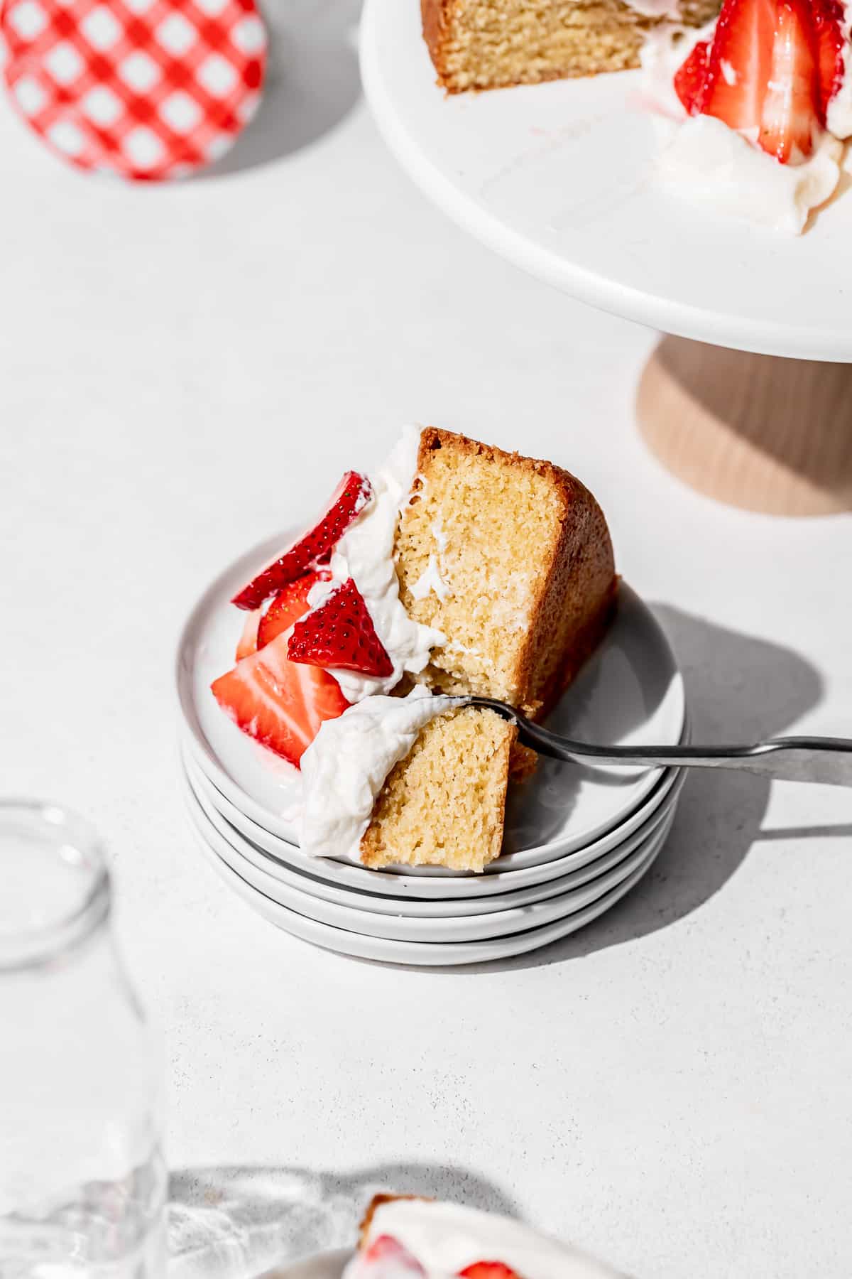 slice of strawberry shortcake cake on stacked white plates.