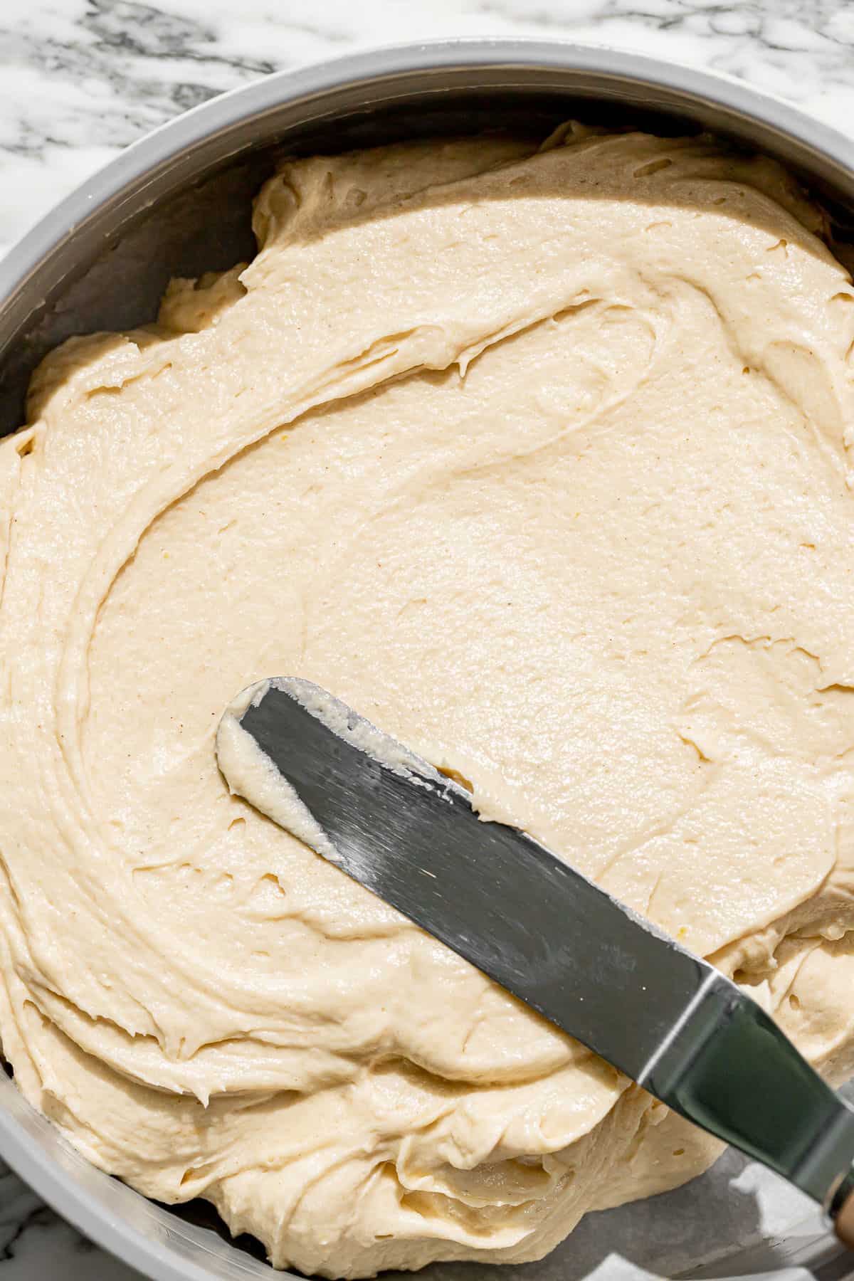 cake batter being spread into cake pan.