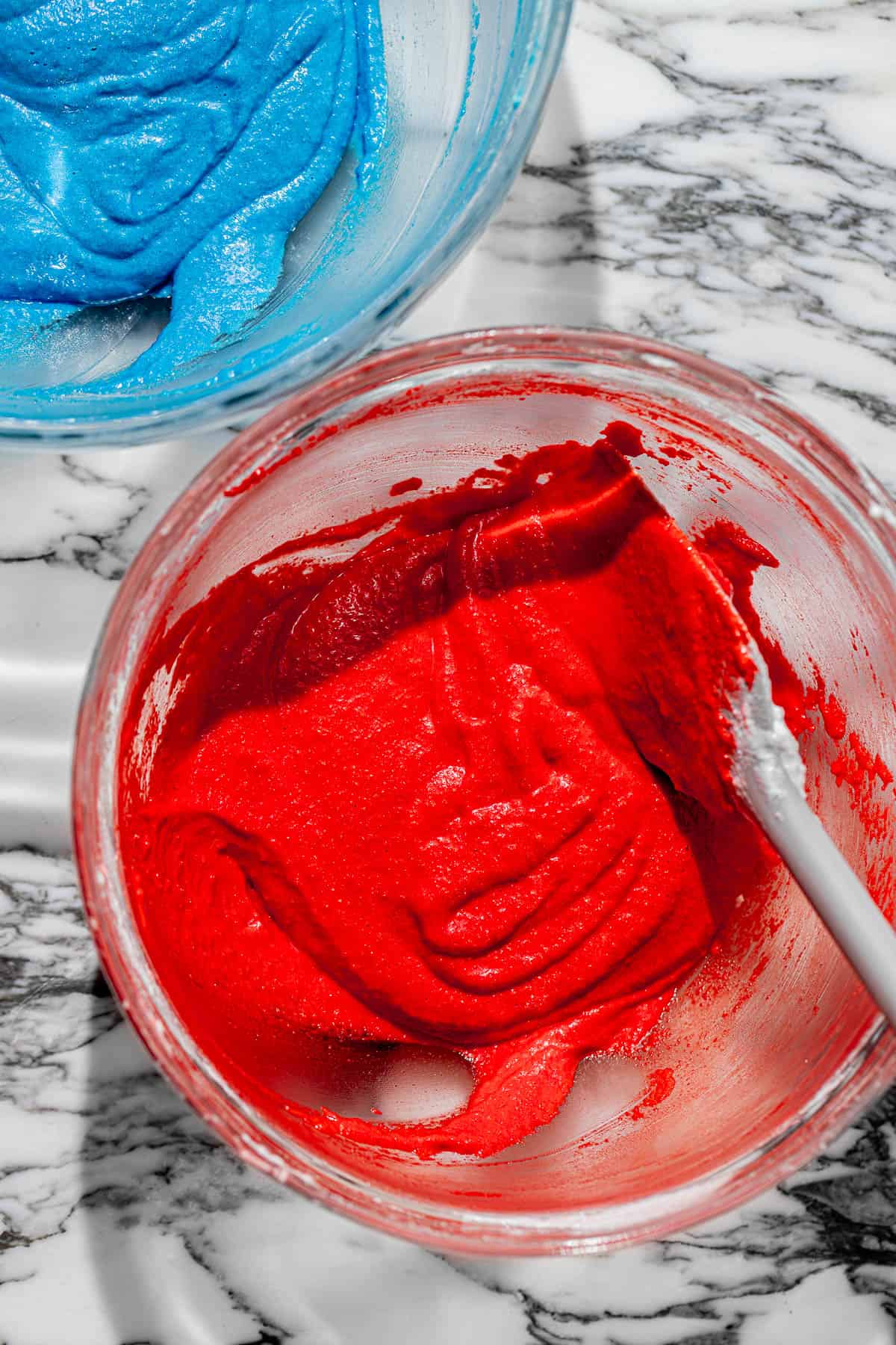 red and blue macaron batter in two bowls.