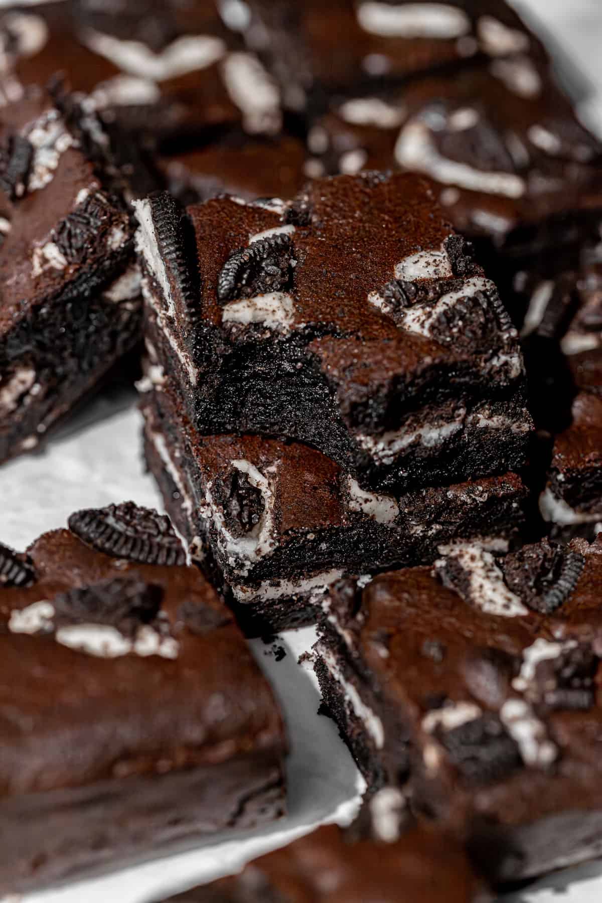 close up of decadent oreo brownies cut into squares and stacked.