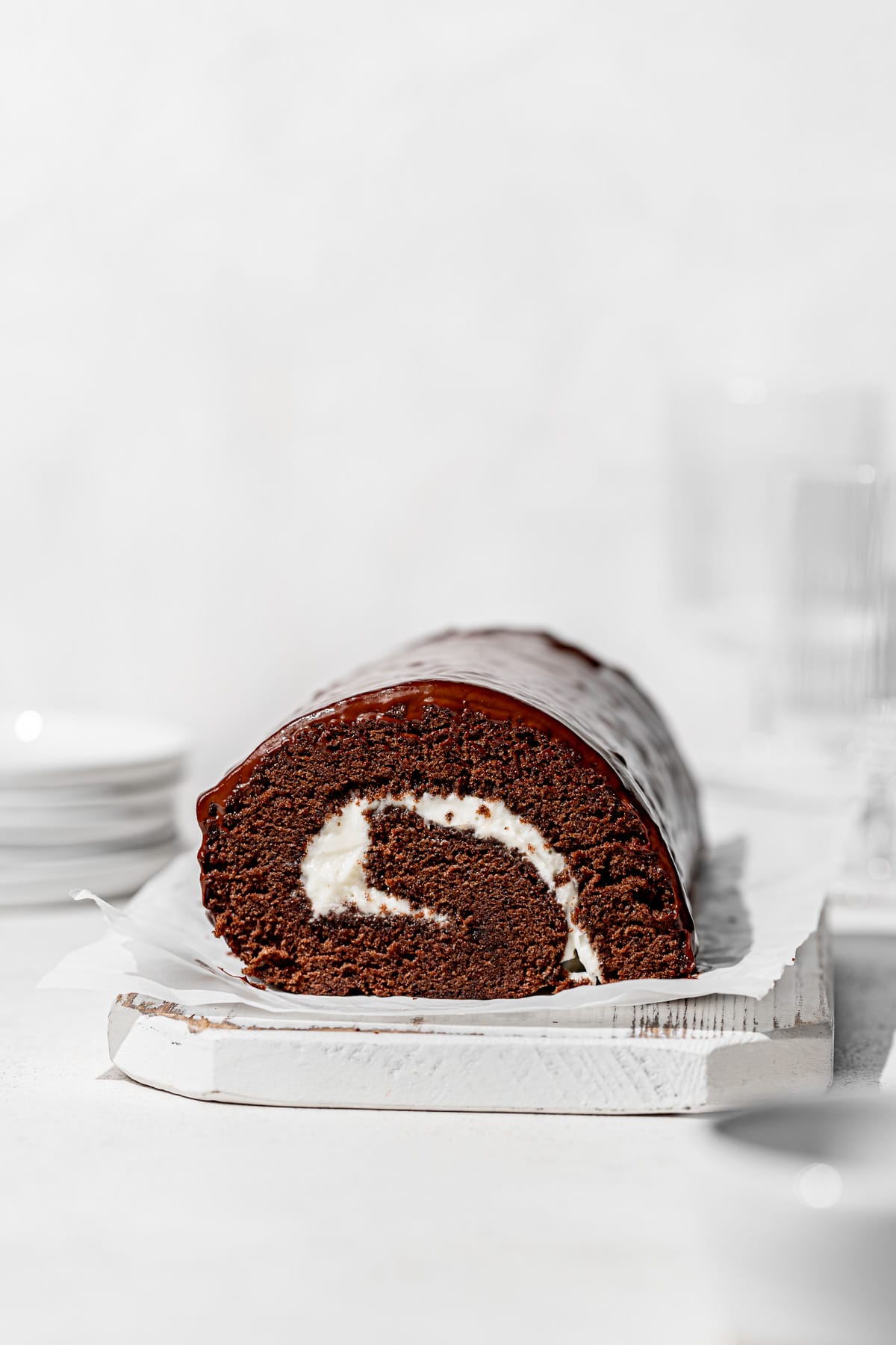 chocolate swiss roll on white wooden board. 
