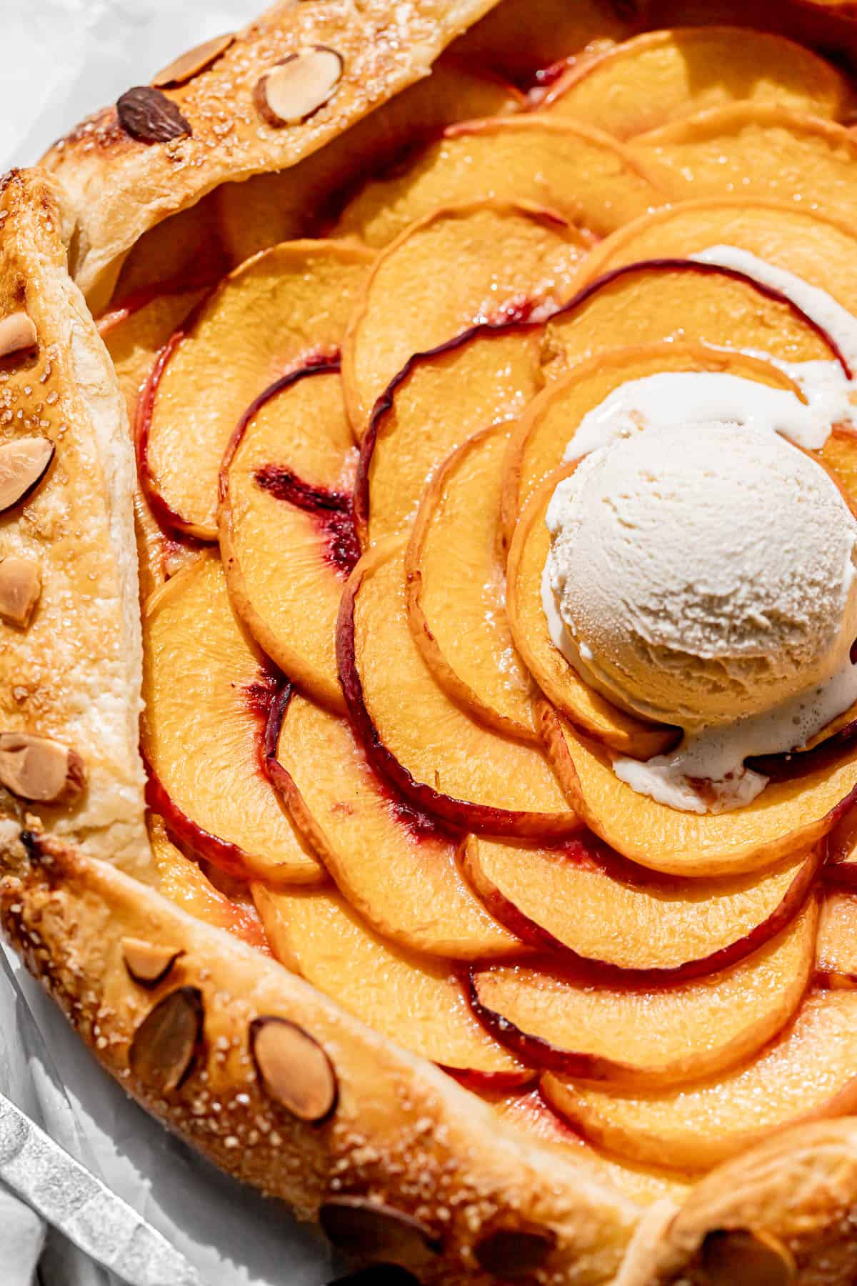 baked almond peach galette with scoop of ice cream on top. 