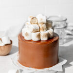 s'mores cake with marshmallows on white wooden board.