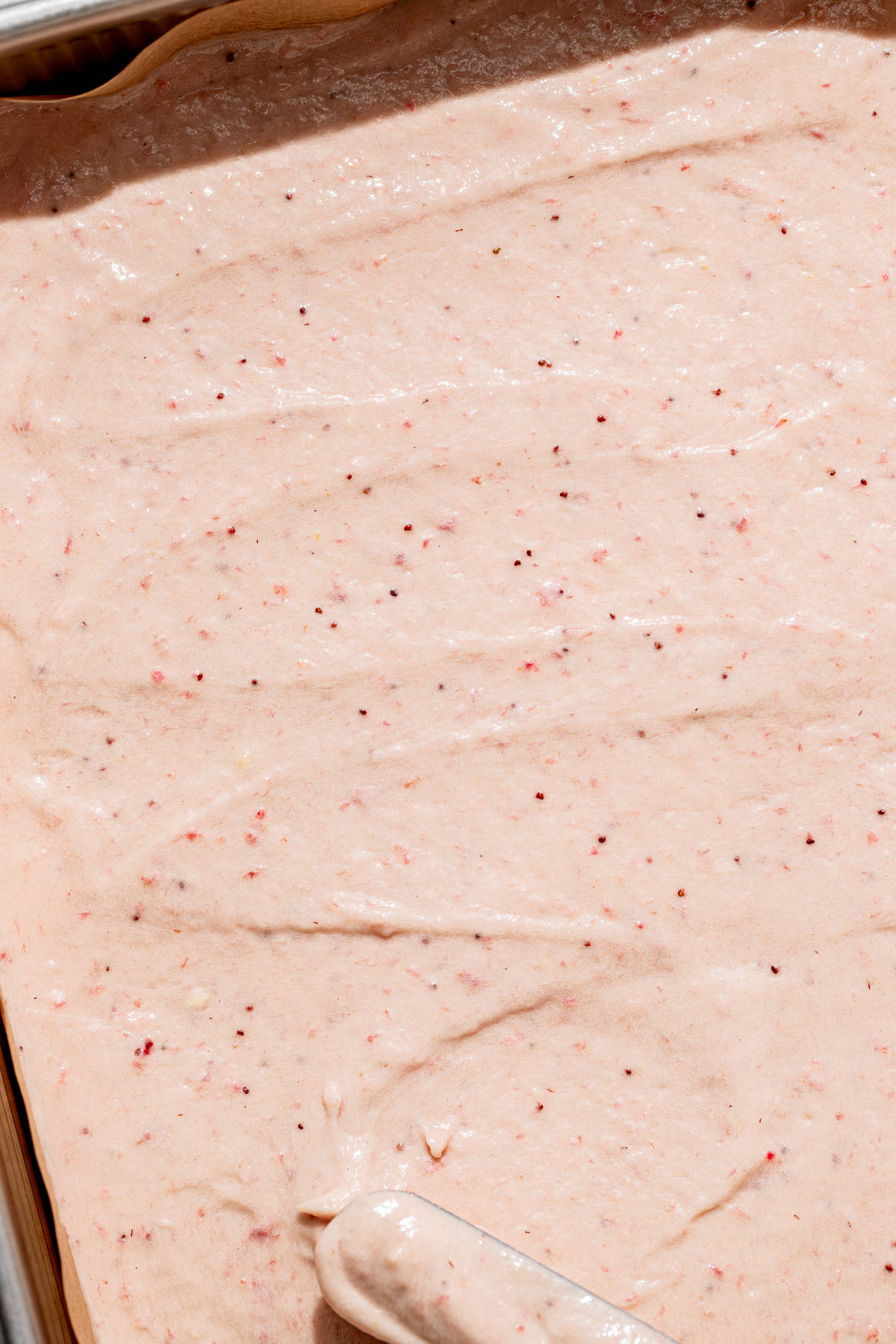 strawberry cake batter spread into baking pan.