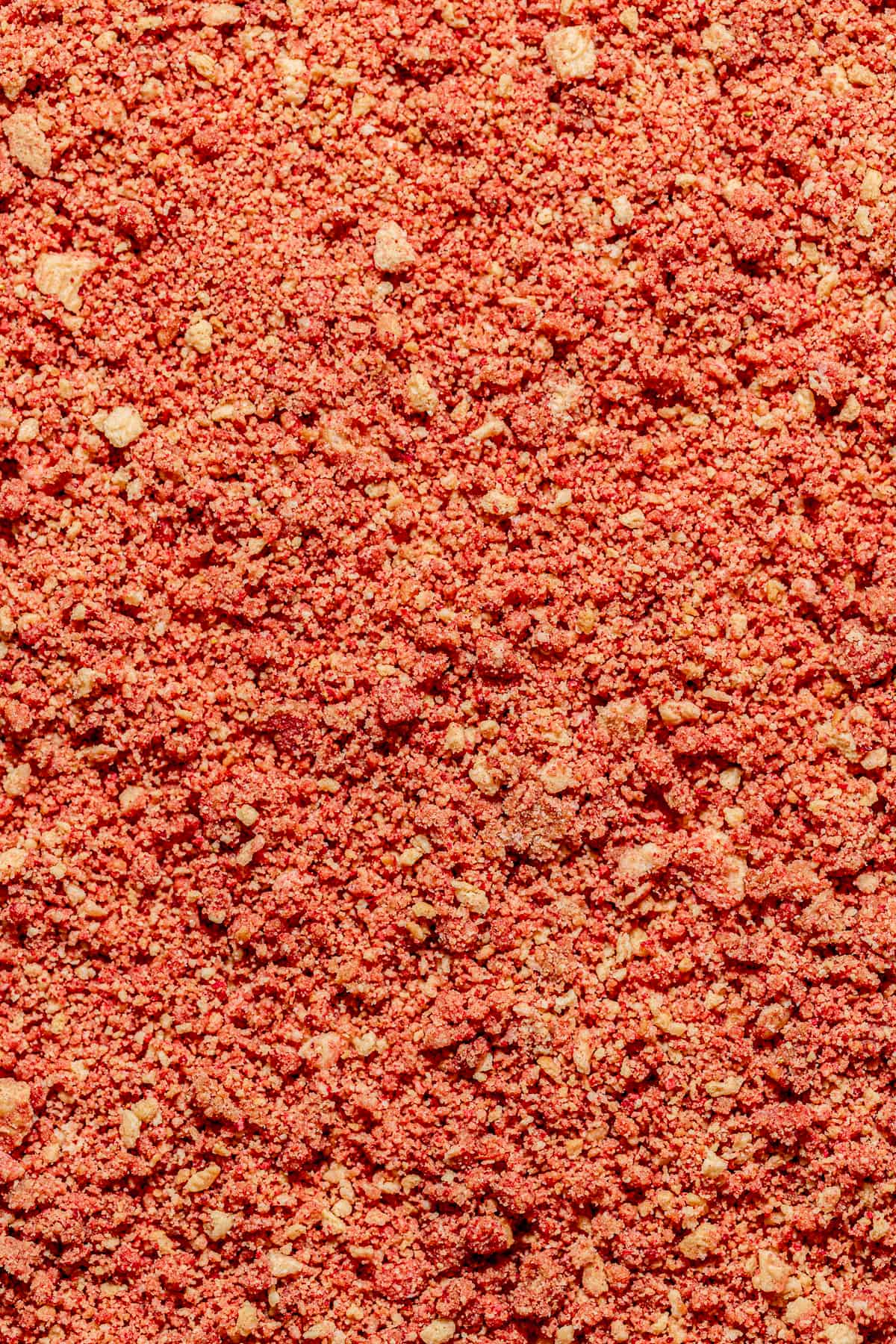 close up of crushed strawberry topping spread onto cake.