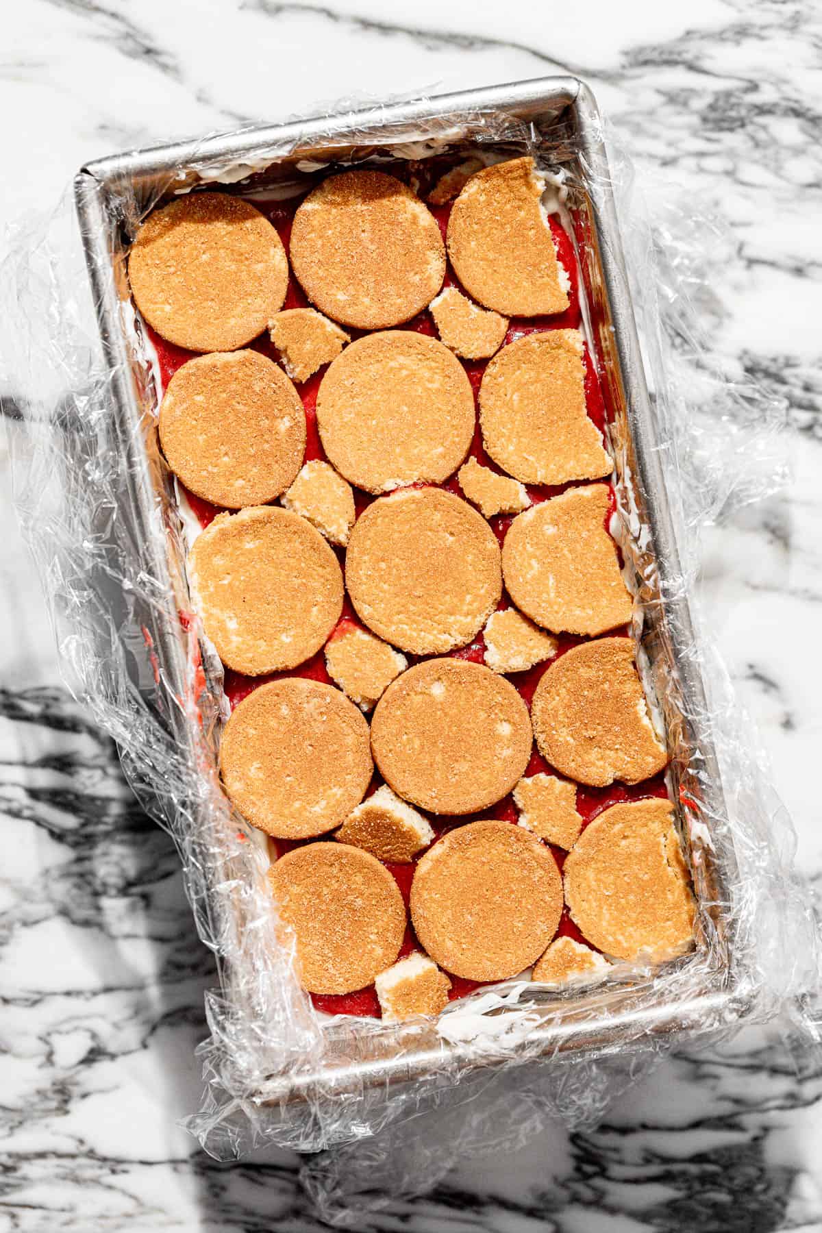 layers of roasted strawberry icebox cake in a loaf pan before fully assembled.