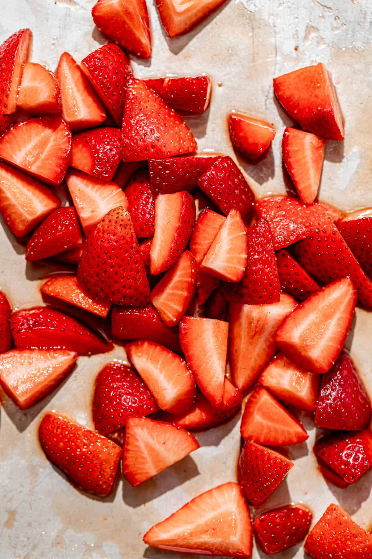 cut strawberries laying on a baking tray.