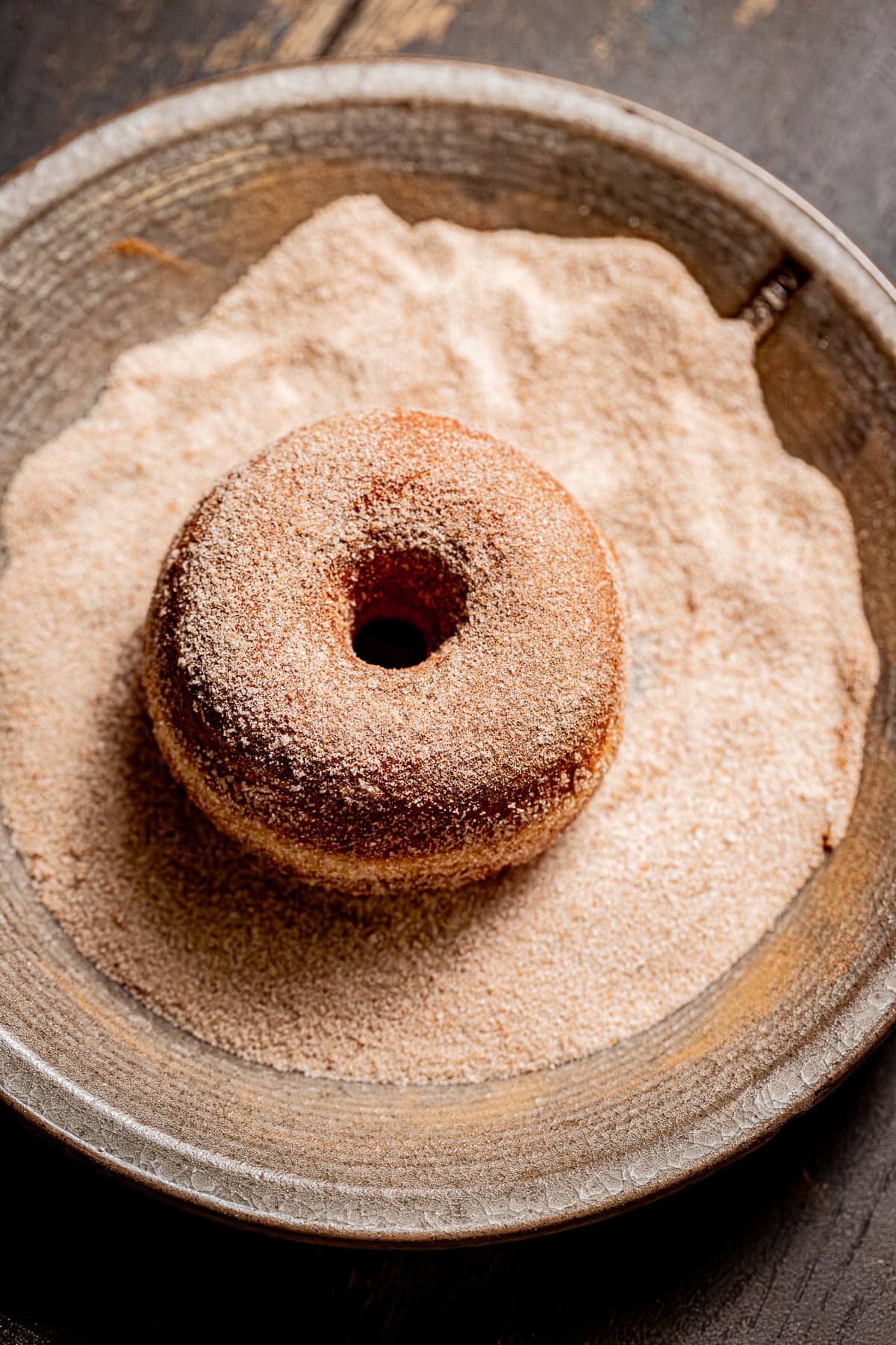 brioche donut in bowl of cinnamon sugar.