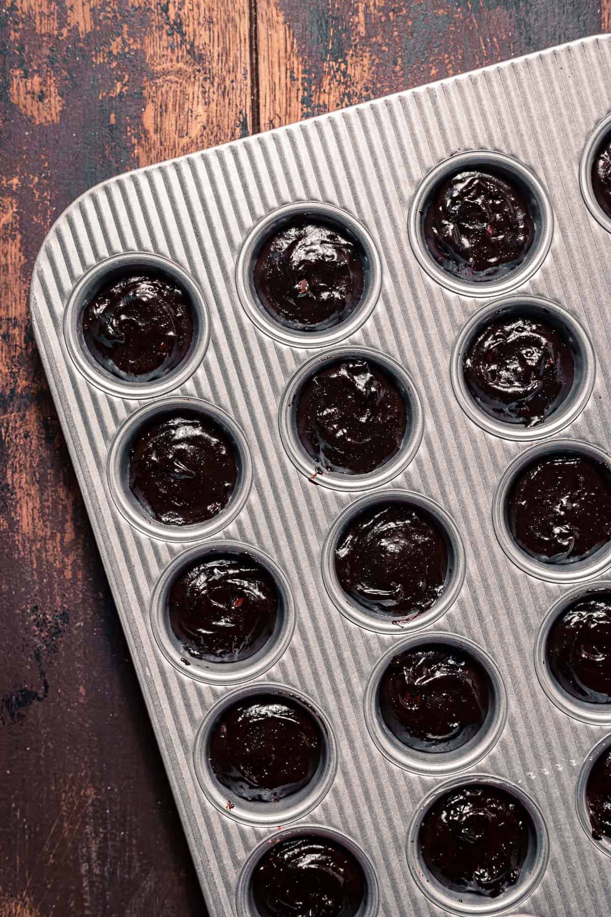 muffin tin with brownie batter in each cup.