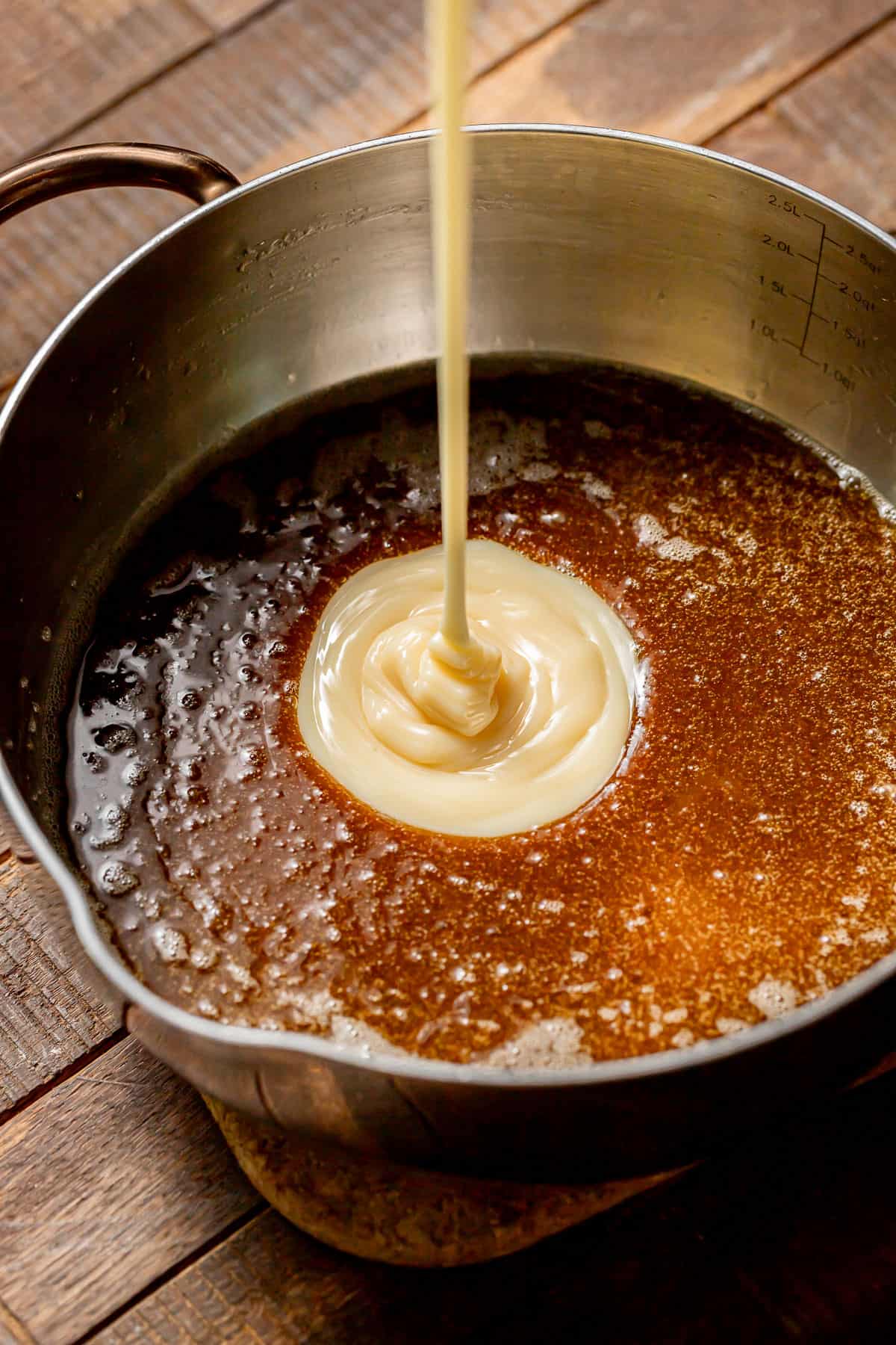 sweetened condensed milk added to caramel in sauce pot.