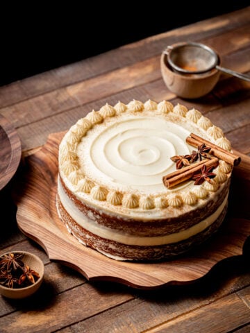 brown sugar chai cake with cream cheese frosting on wooden platter.