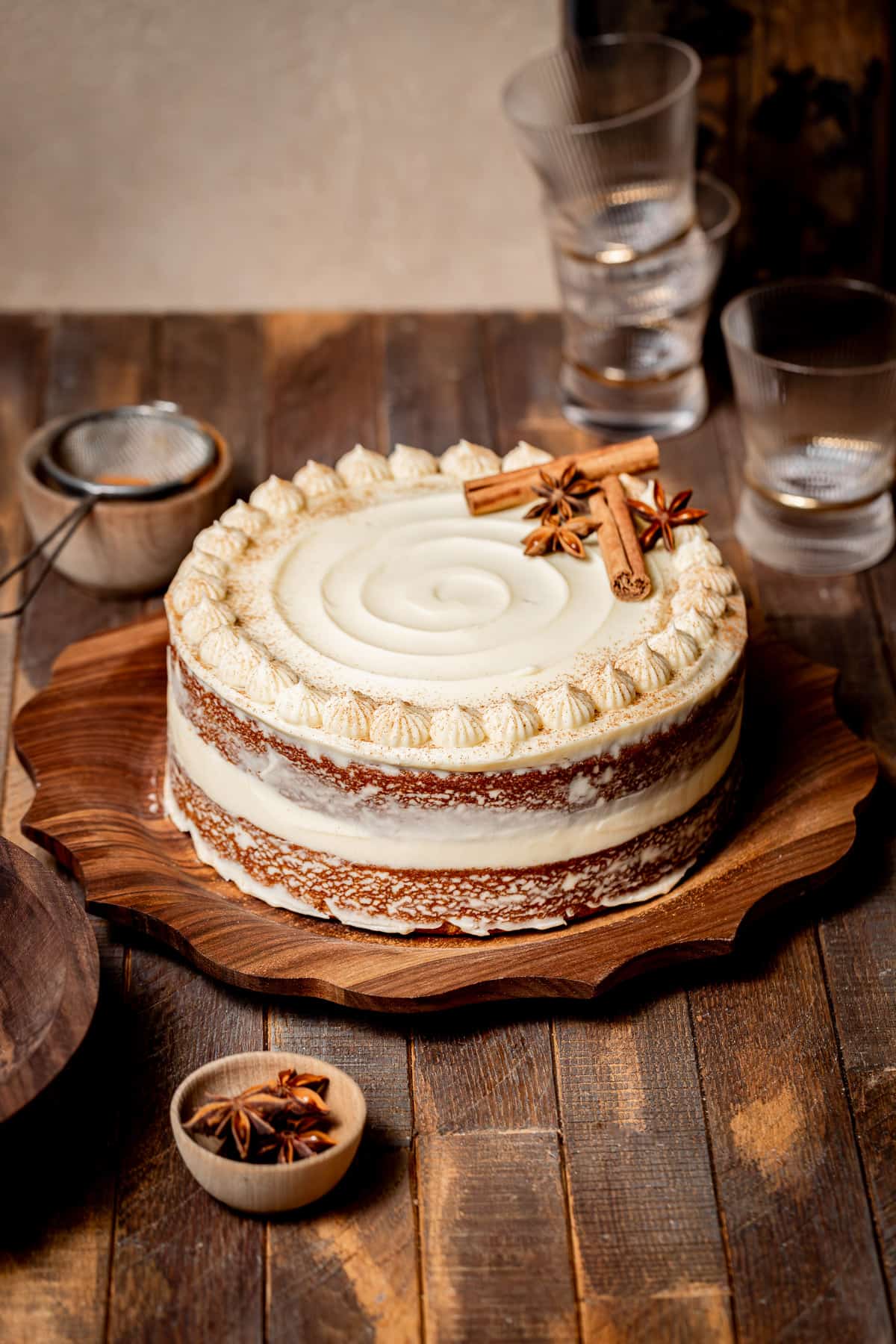 brown sugar chai cake with cream cheese frosting on wooden platter.