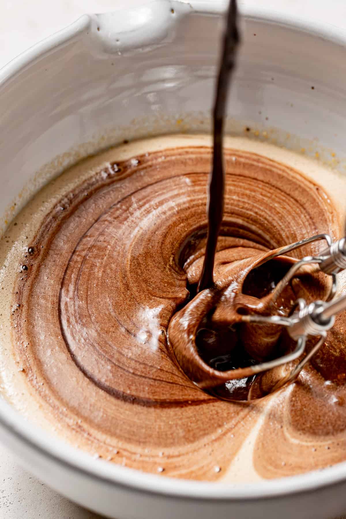 chocolate mixture added to wet ingredients in bowl.
