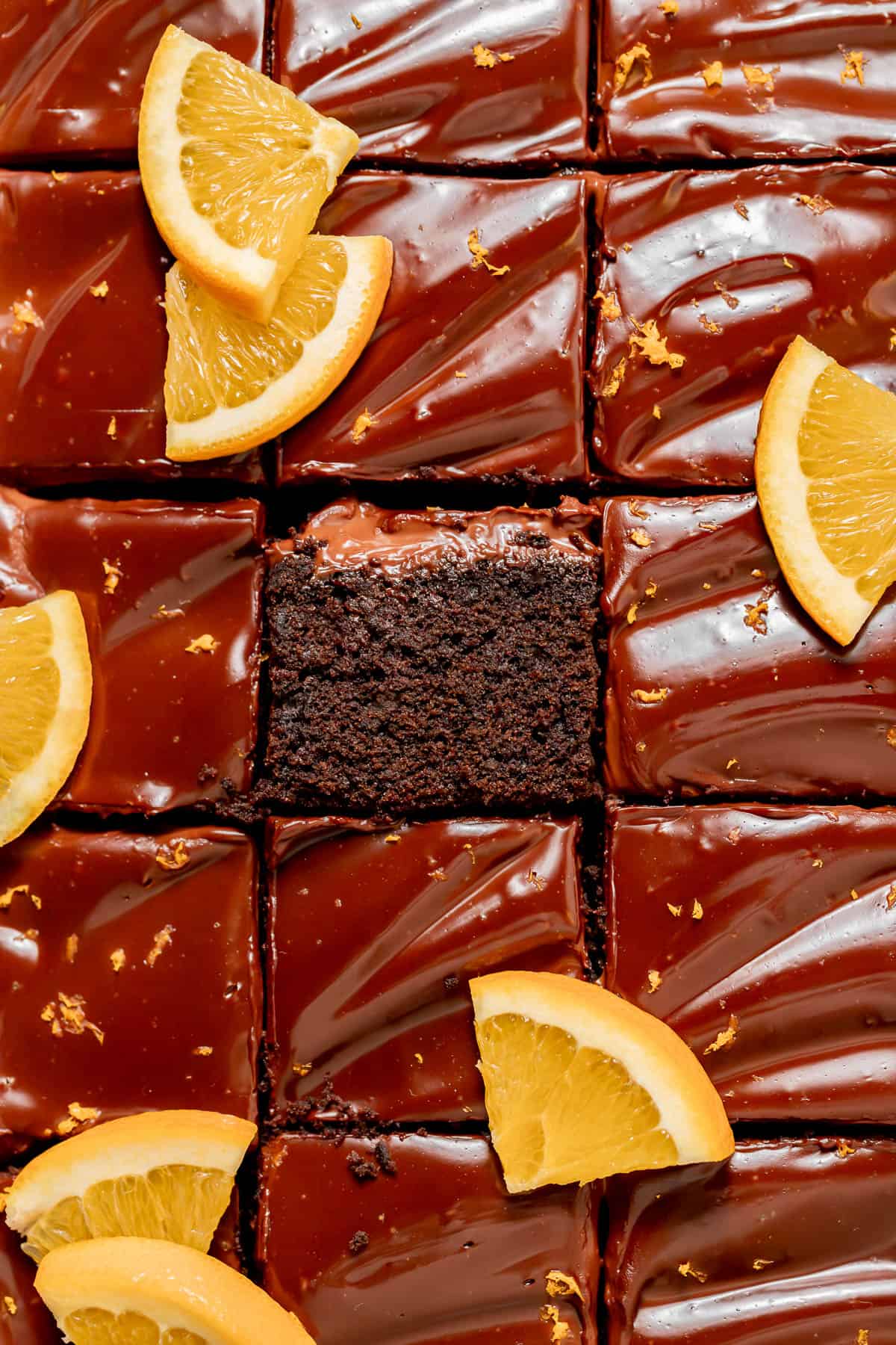 chocolate orange cake cut into squares with orange slices on top.