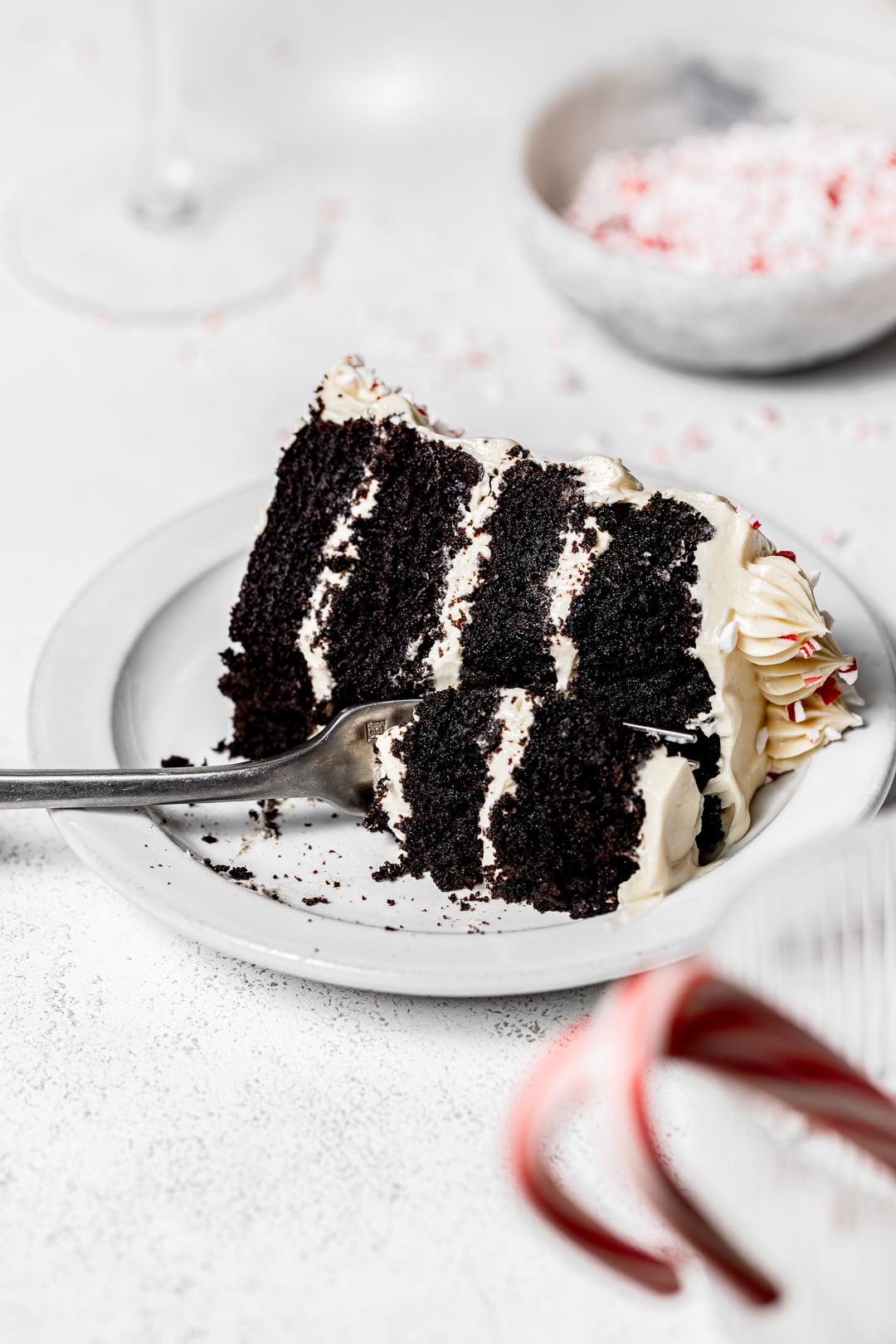 slice of chocolate peppermint cake on a white plate with fork cutting through.