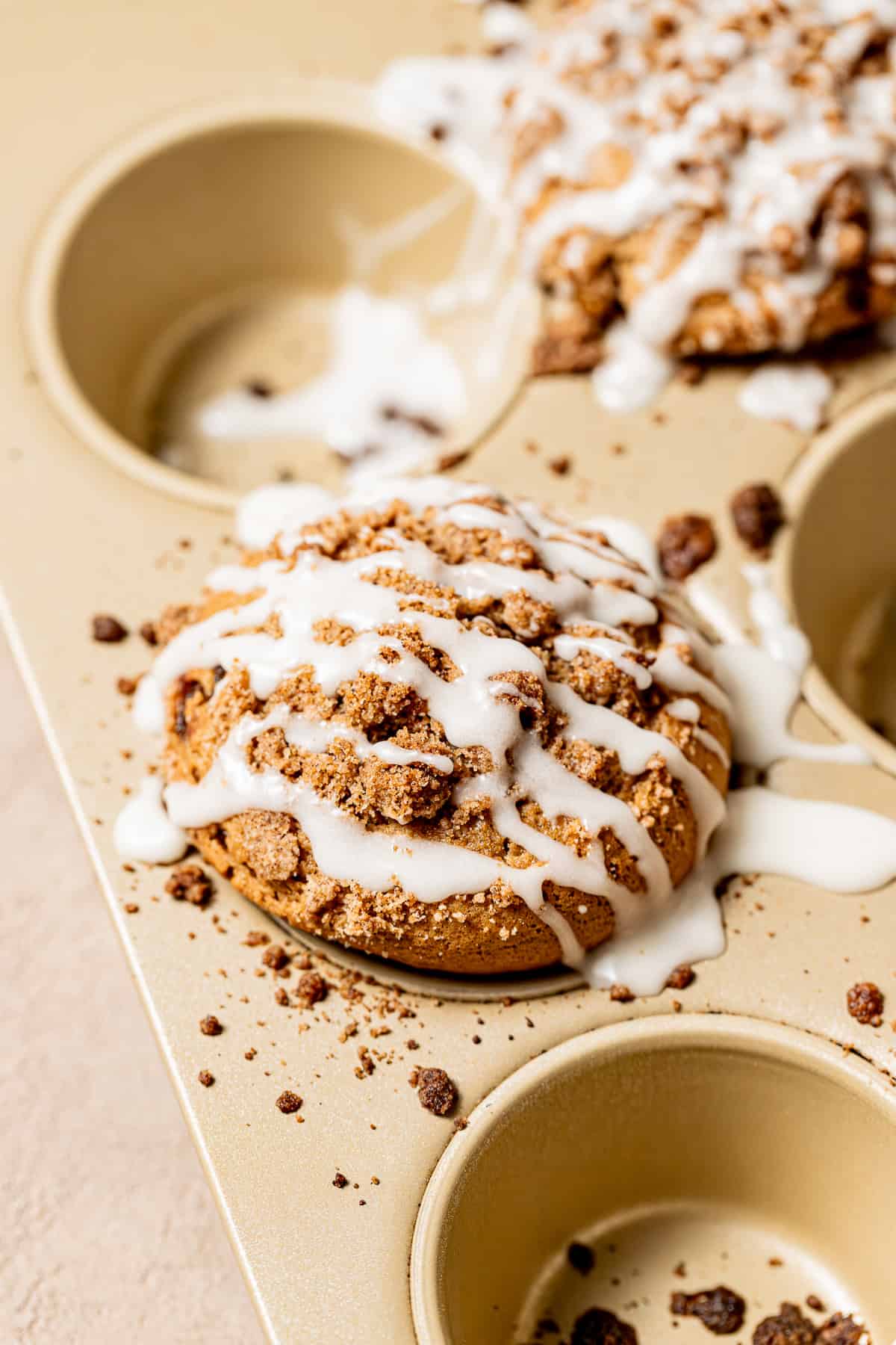 coffee coffee cake muffins baked in muffin tin with crumb topping and glaze.
