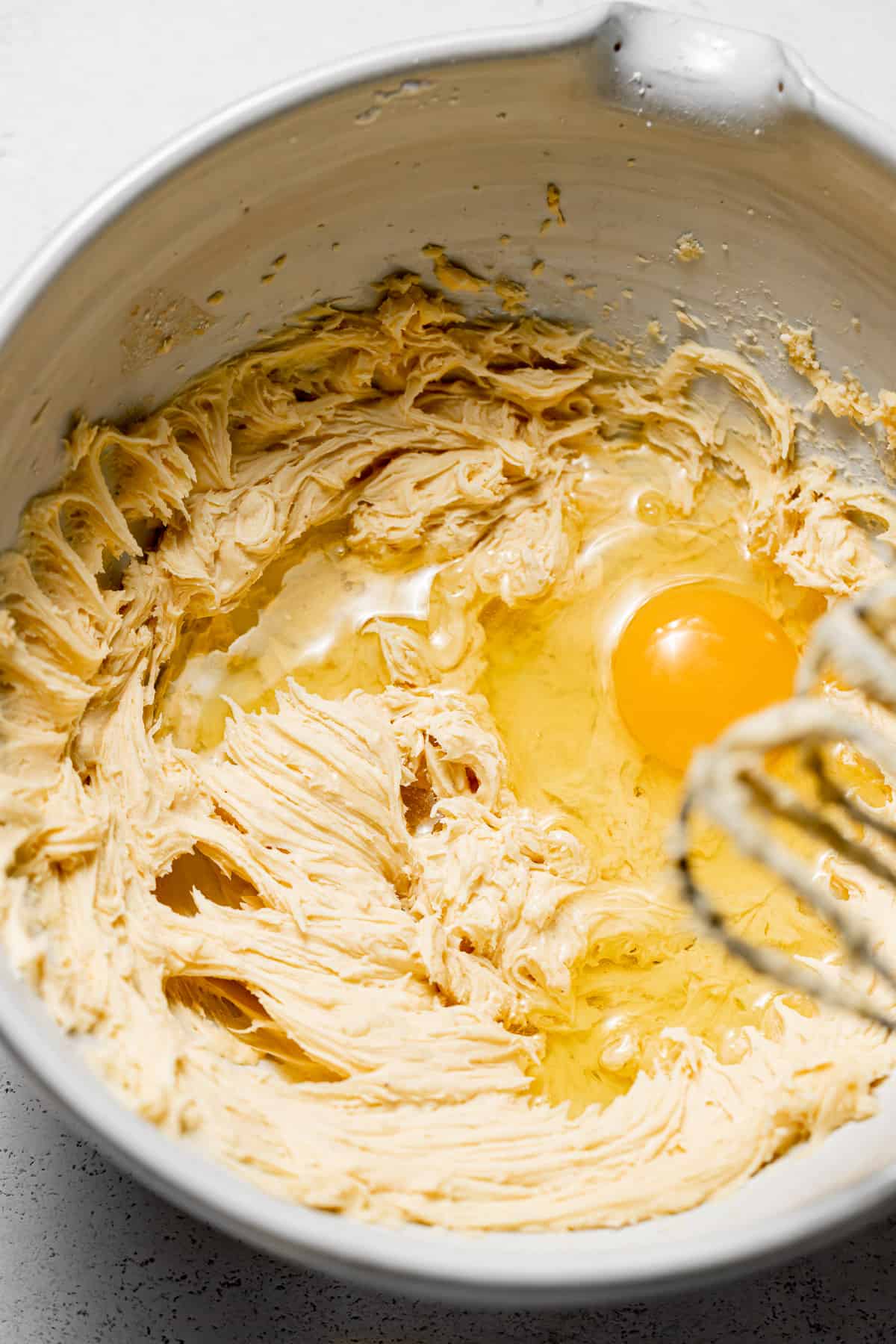 eggs added to butter mixture in white bowl with whisk.