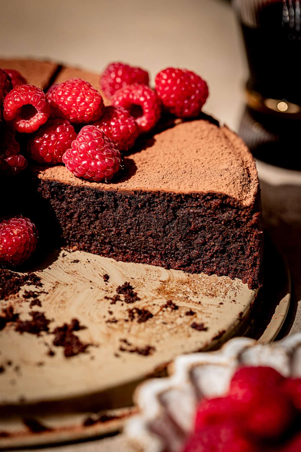 red wine chocolate cake with fresh raspberries on top with slice taken out.