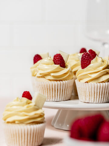 white chocolate raspberry cupcakes on white cake stand.