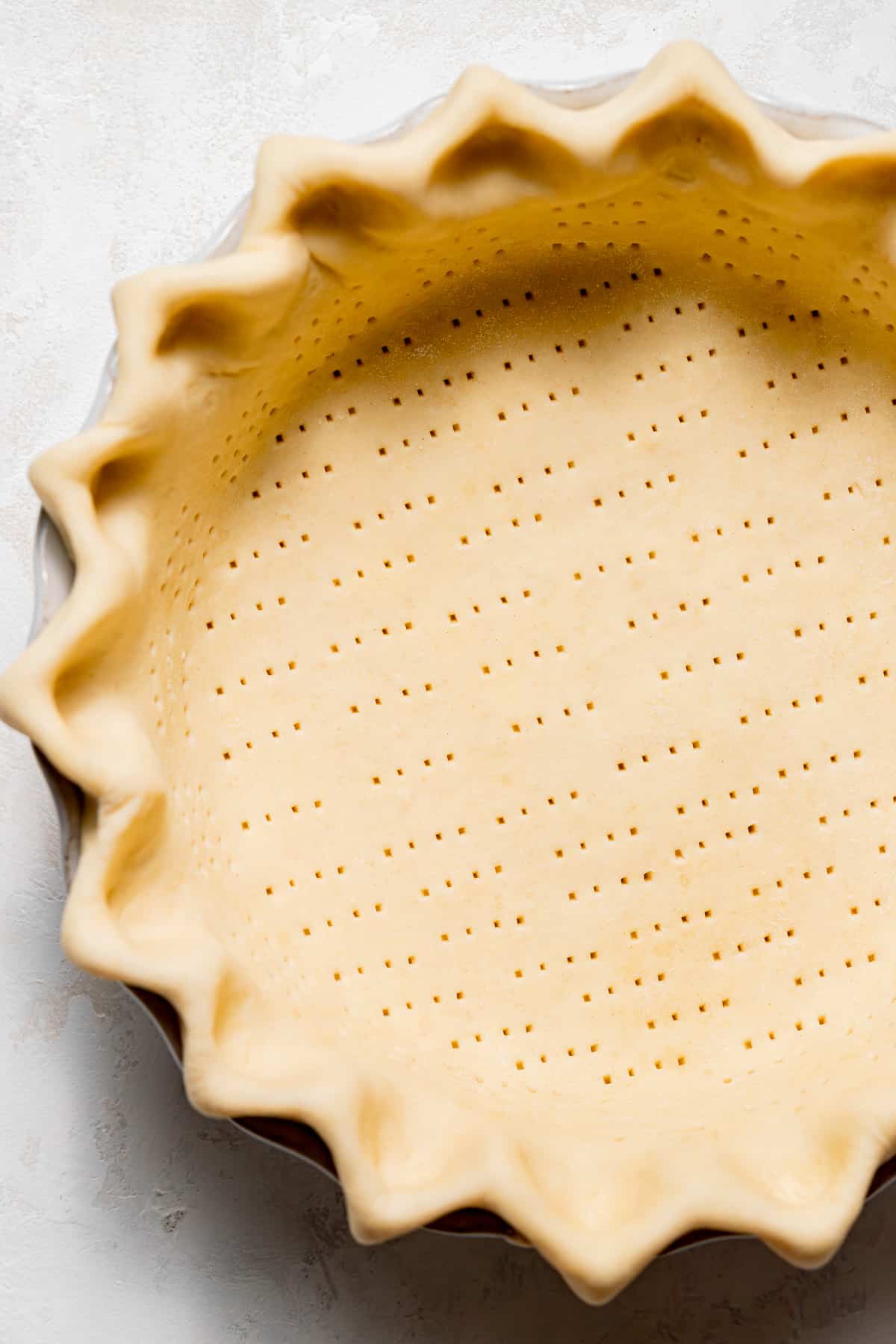 pie dough pressed into pie pan with crimped edges and docked center.