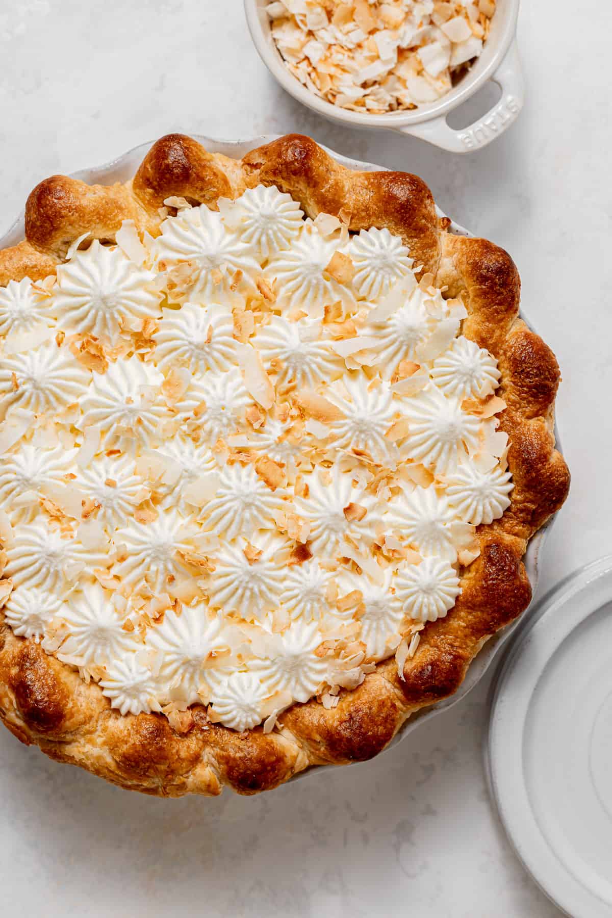 coconut pie with piped whipped cream and toasted coconut on top.
