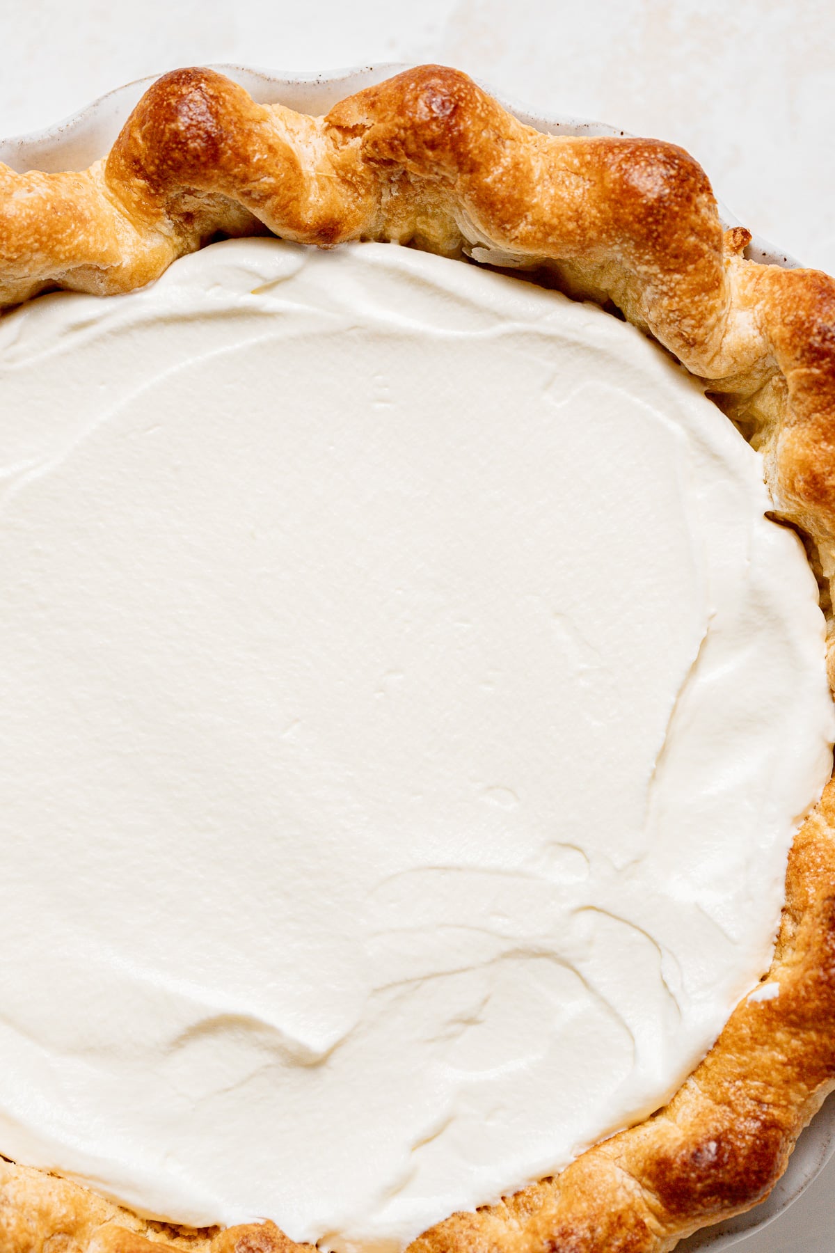 whipped cream spread on top of coconut pie.
