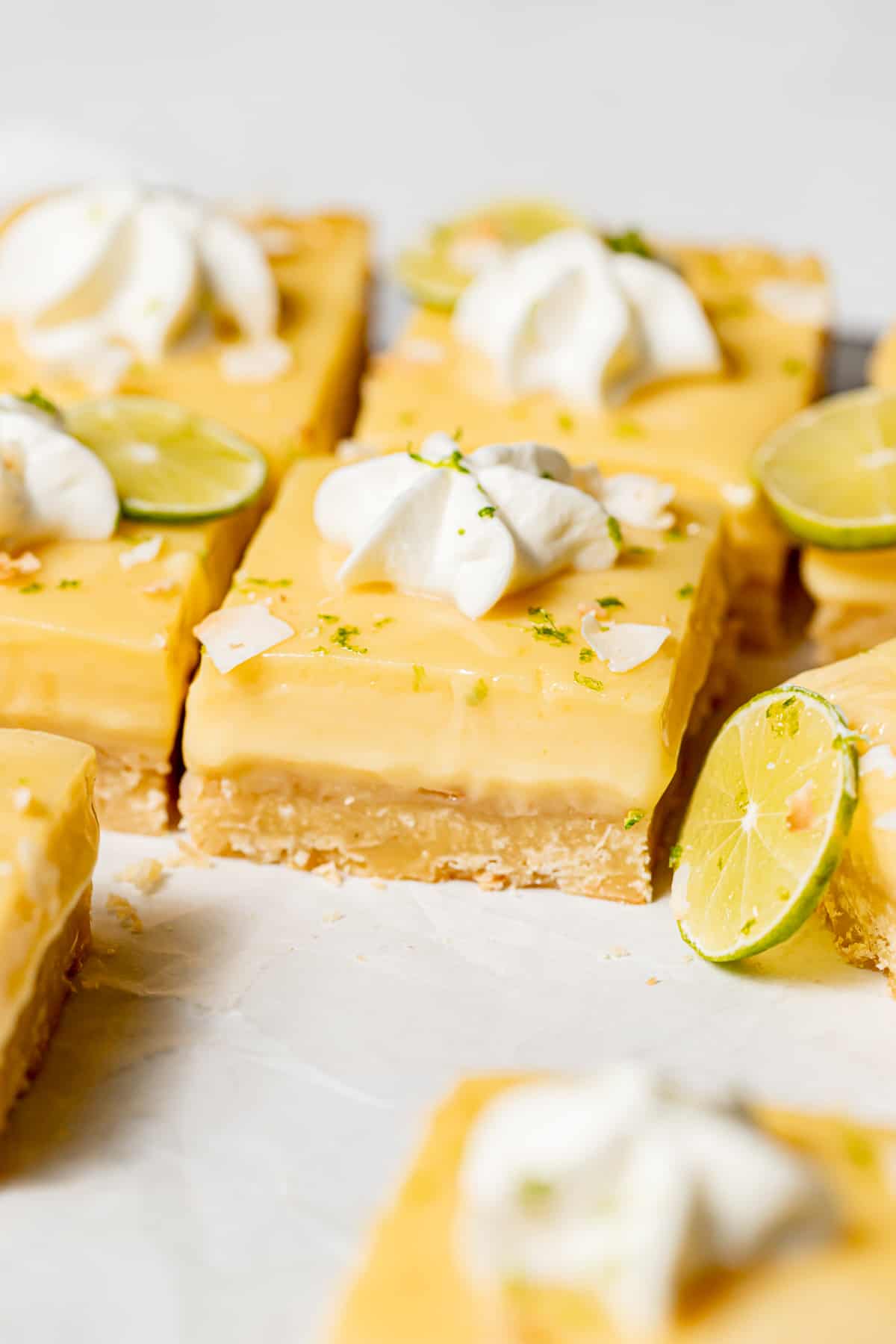close up of coconut key lime bars with dollops of whipped cream.