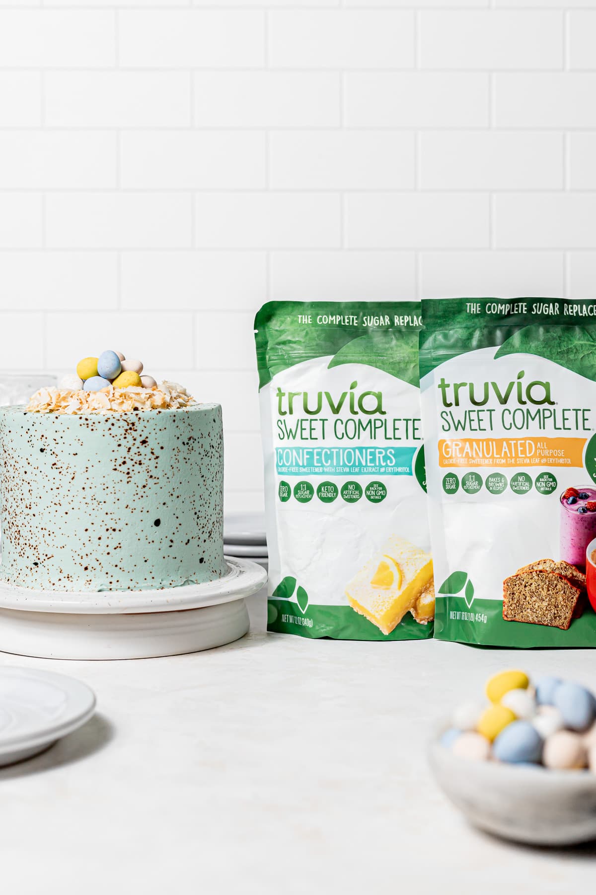 robin's egg easter cake on white cake stand with two bags of truvia sugar.