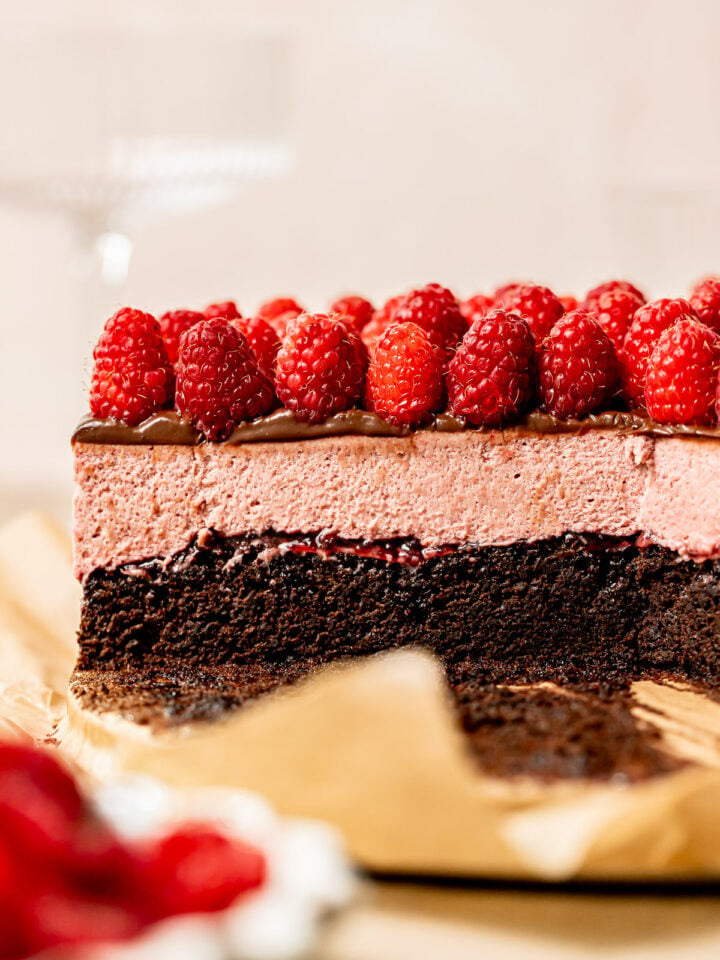 cross section of chocolate raspberry mousse cake with fresh raspberries on top.