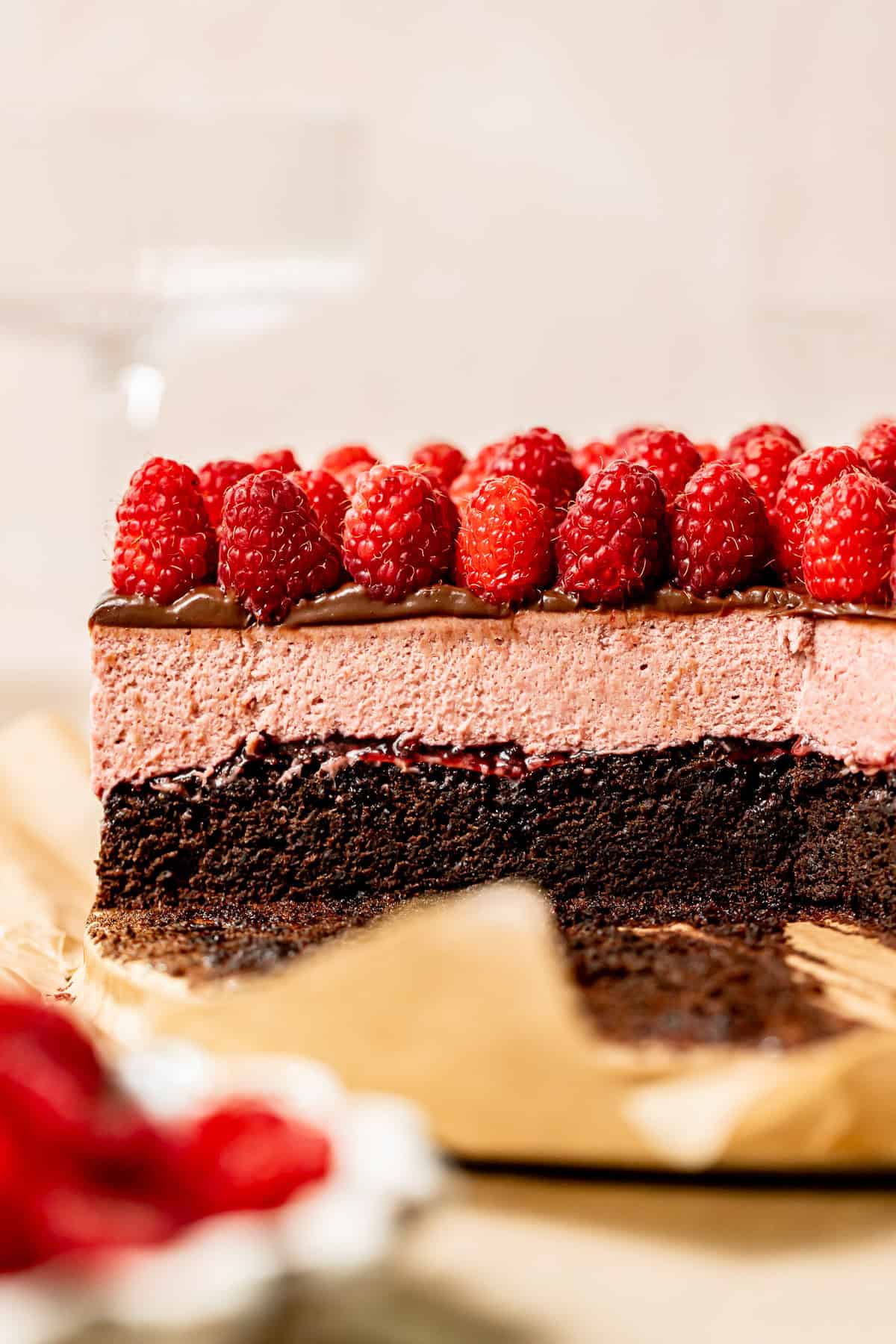 cross section of chocolate raspberry mousse cake with fresh raspberries on top.