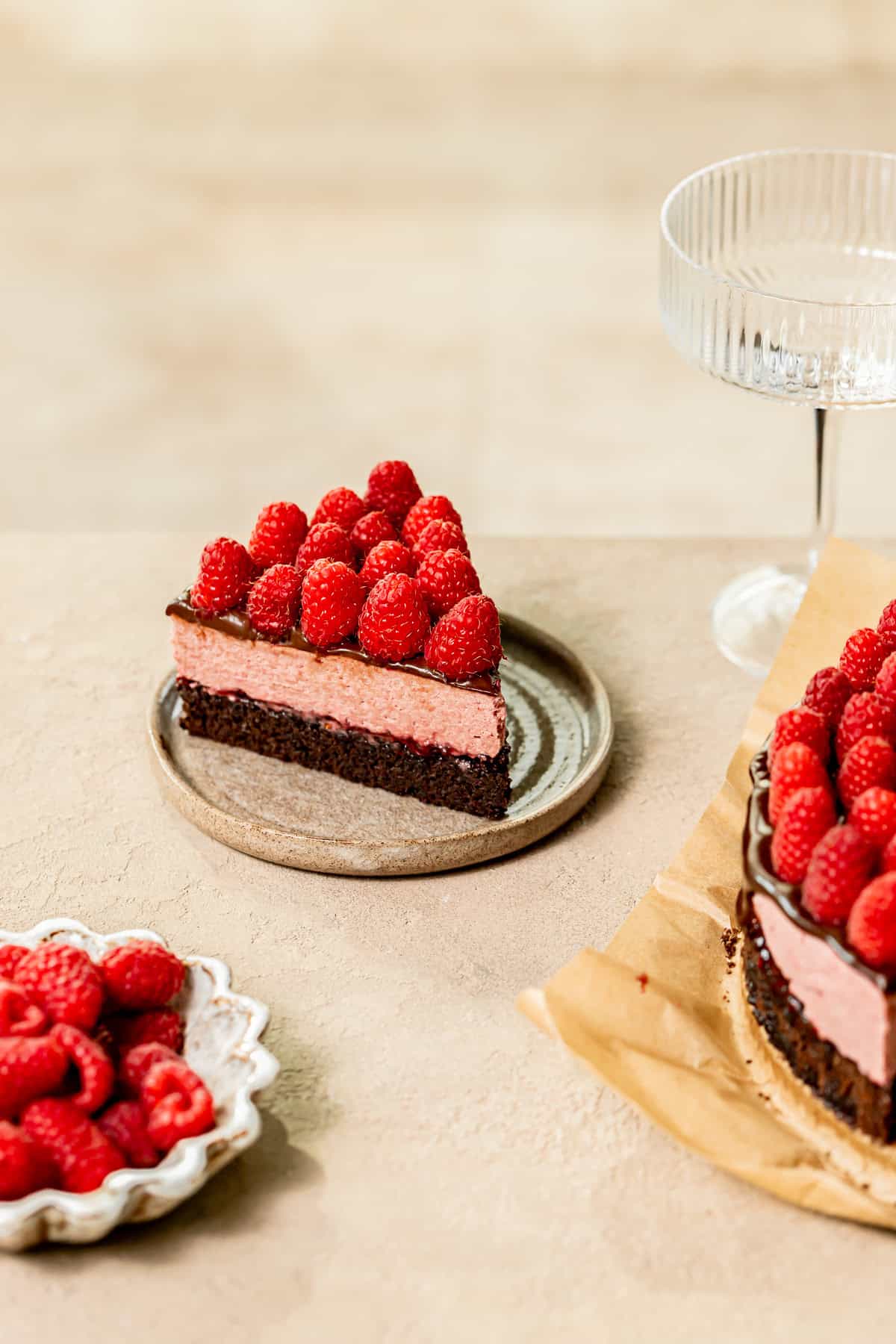 slice of chocolate raspberry mousse cake on small plate with fresh raspberries on top.