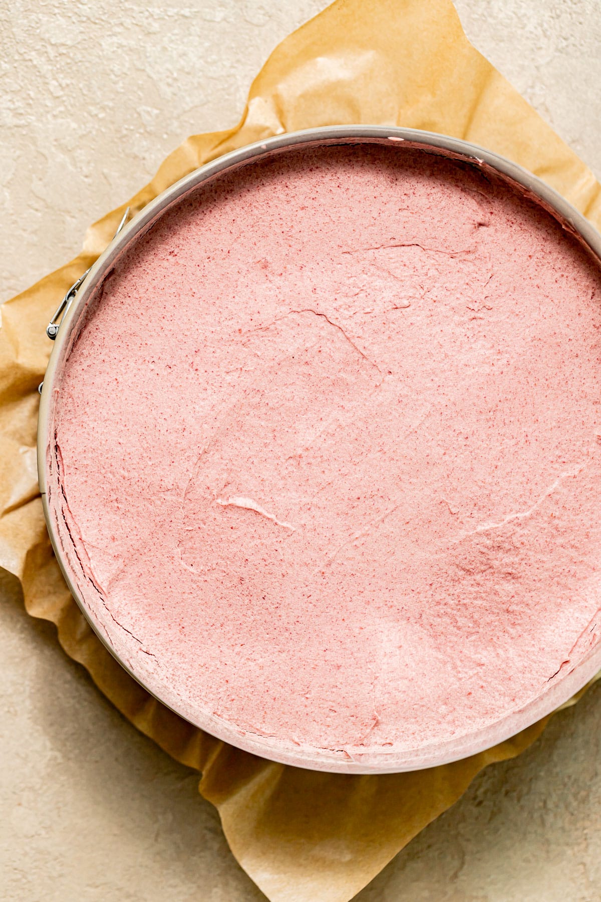 overhead view of raspberry mousse spread onto cake in pan.