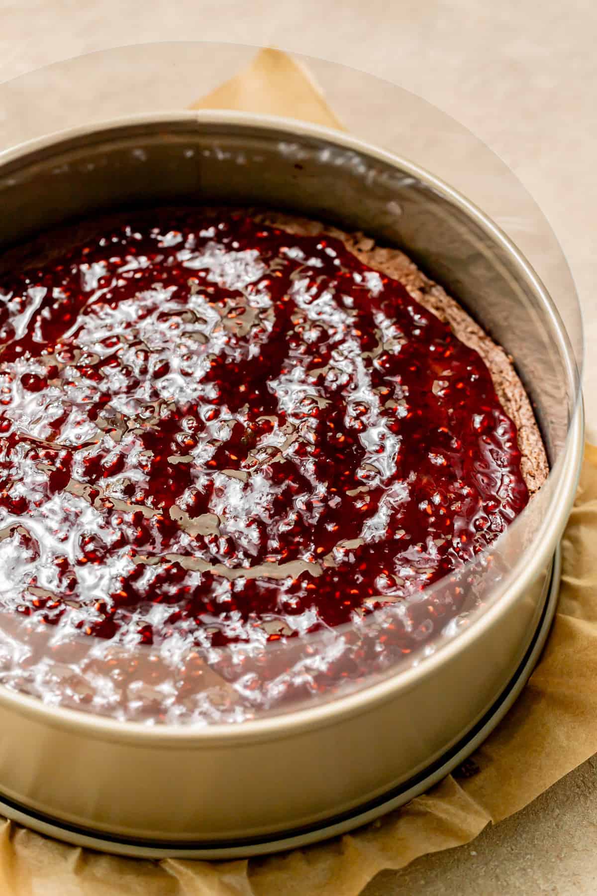 raspberry jam spread onto chocolate cake in springform pan.