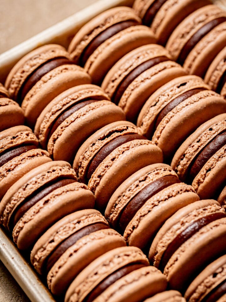 double chocolate macarons lined up on baking sheet.