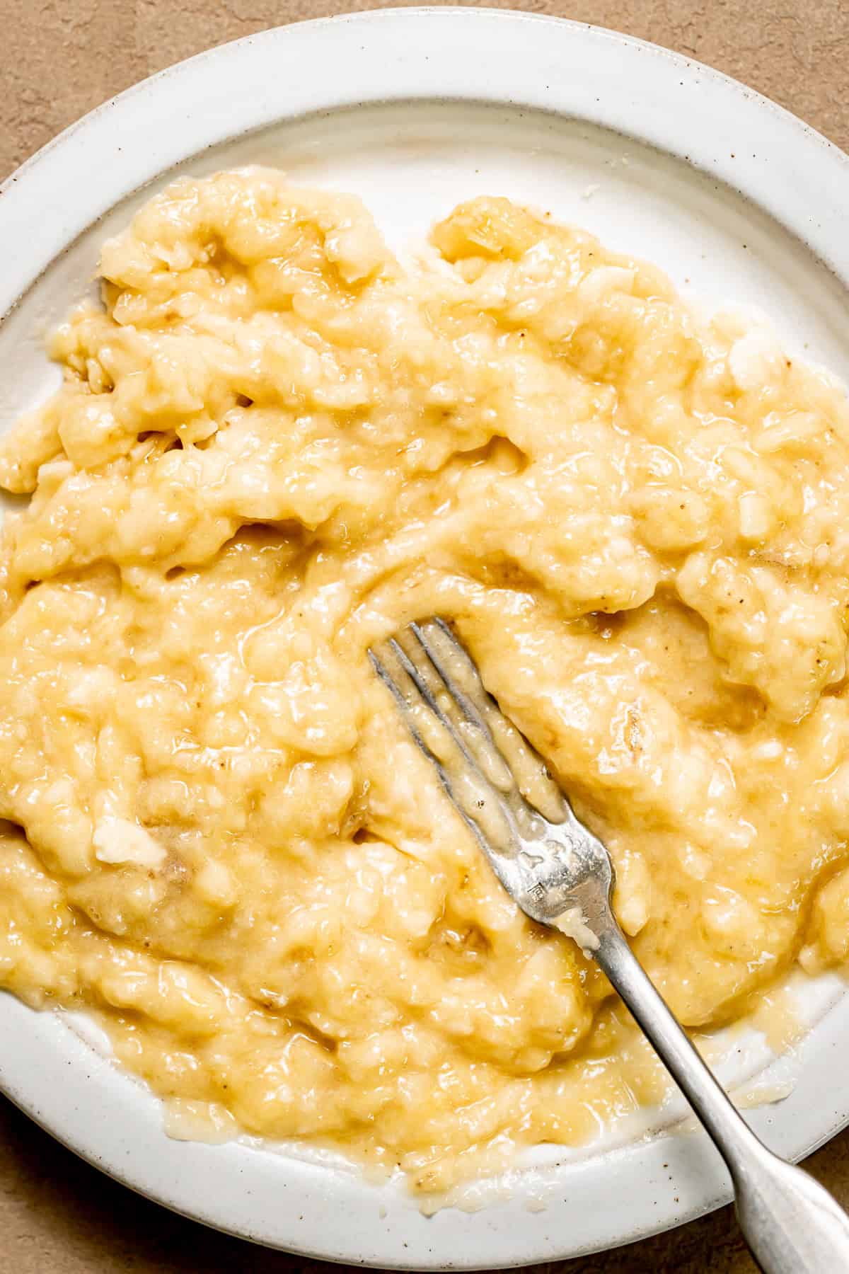 mashed banana on plate with fork.