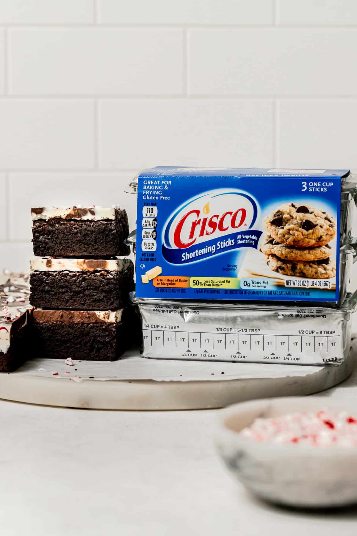 Peppermint Bark Brownies stacked next to Crisco shortening sticks. 