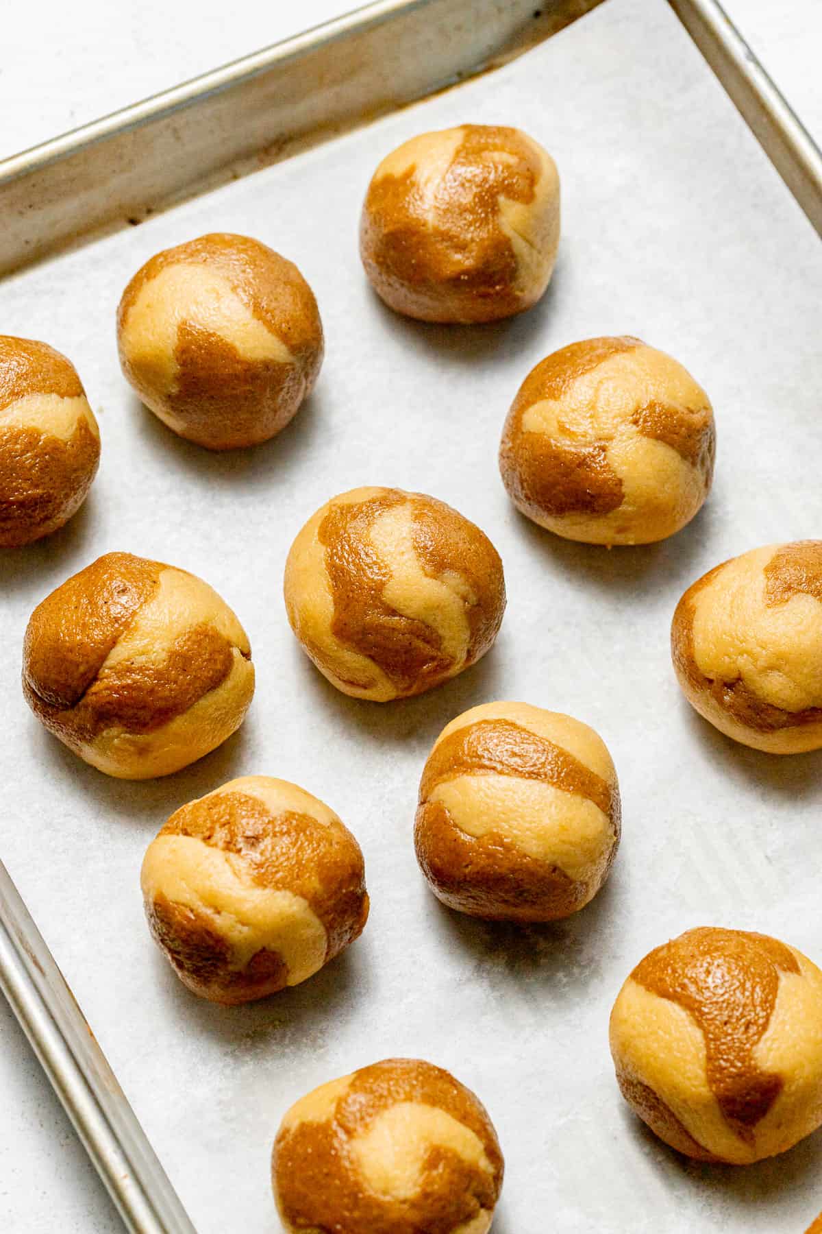 marbled snickerdoodle cookie dough balls on baking sheet. 